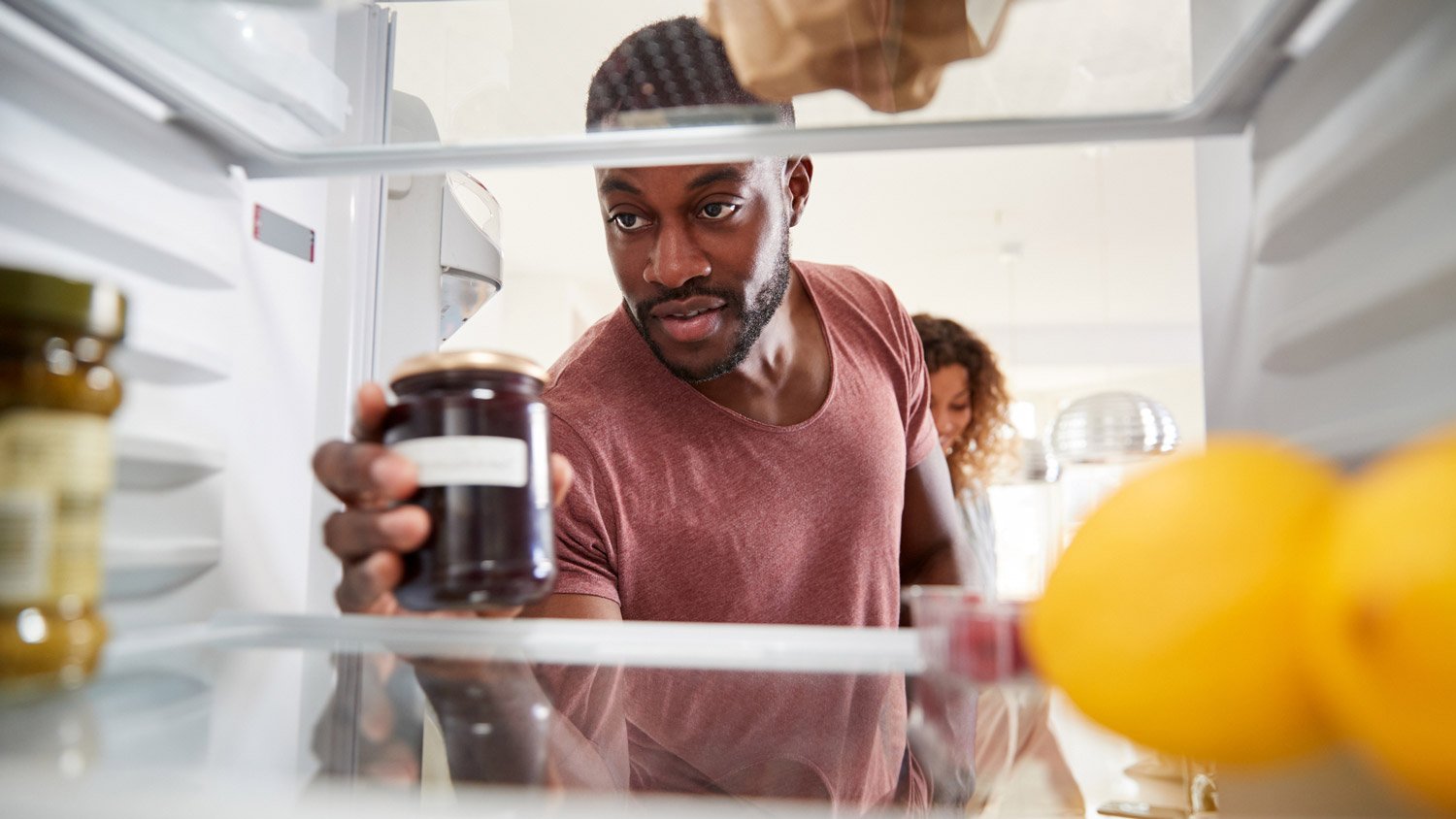 A man placing groceries in the fridge