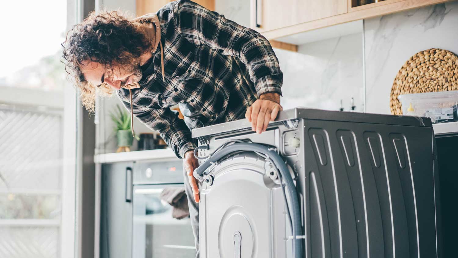 A man unplugging an old washing machine