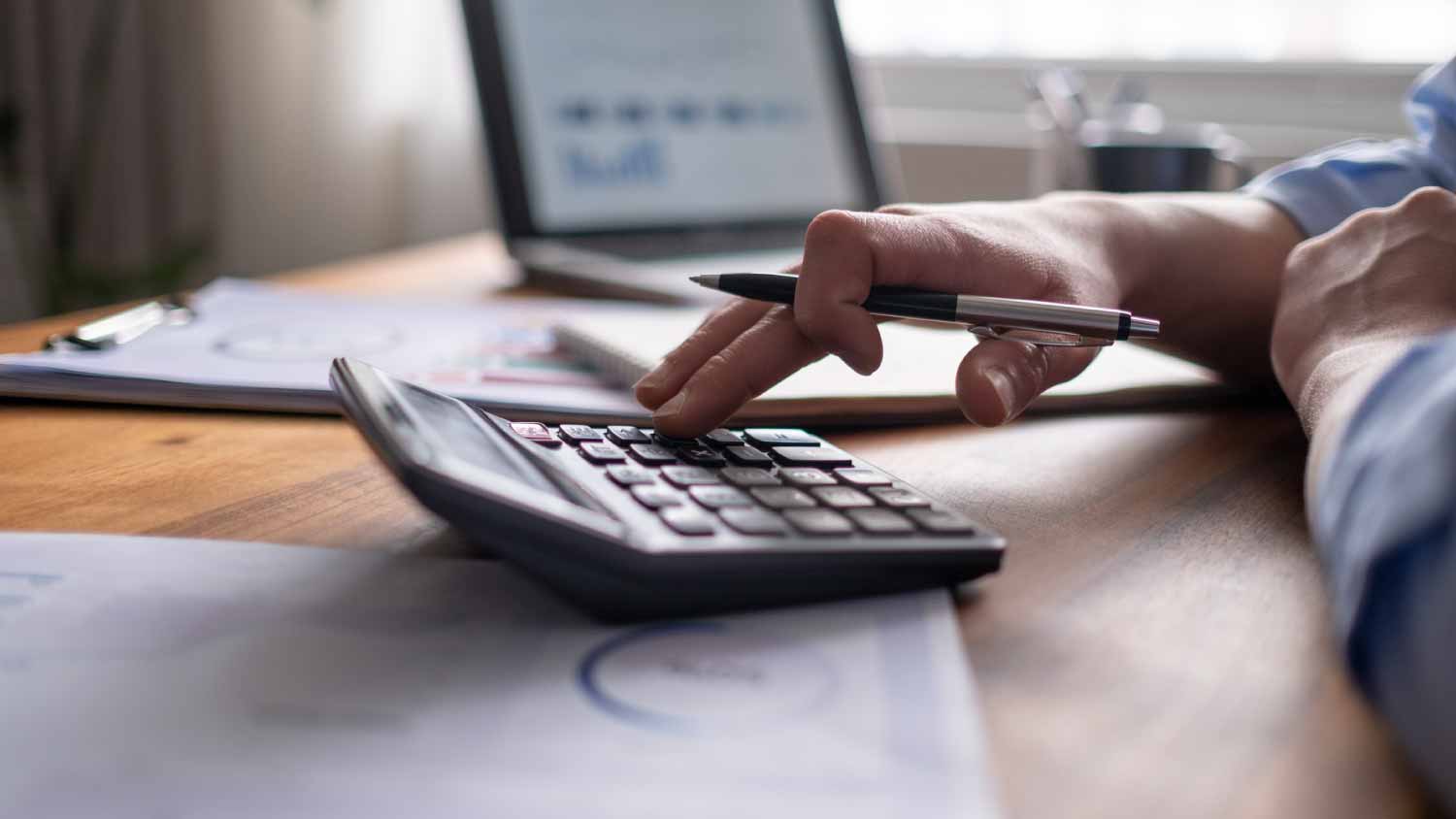 man using calculator and laptop