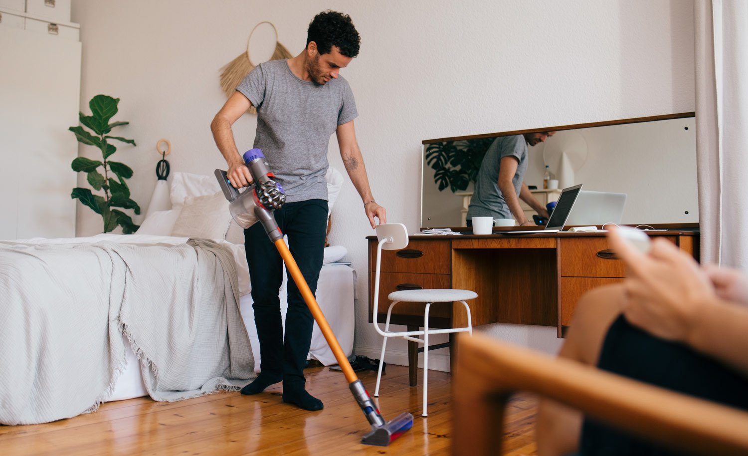 A man vacuums hardwood floor in his apartment