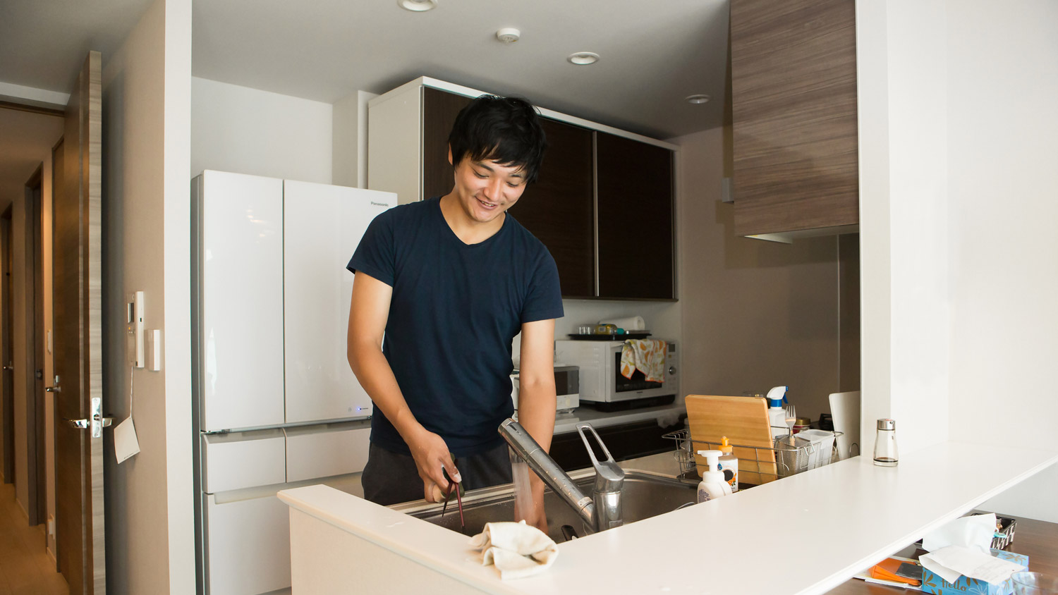 A man washing his coffee mug in the kitchen