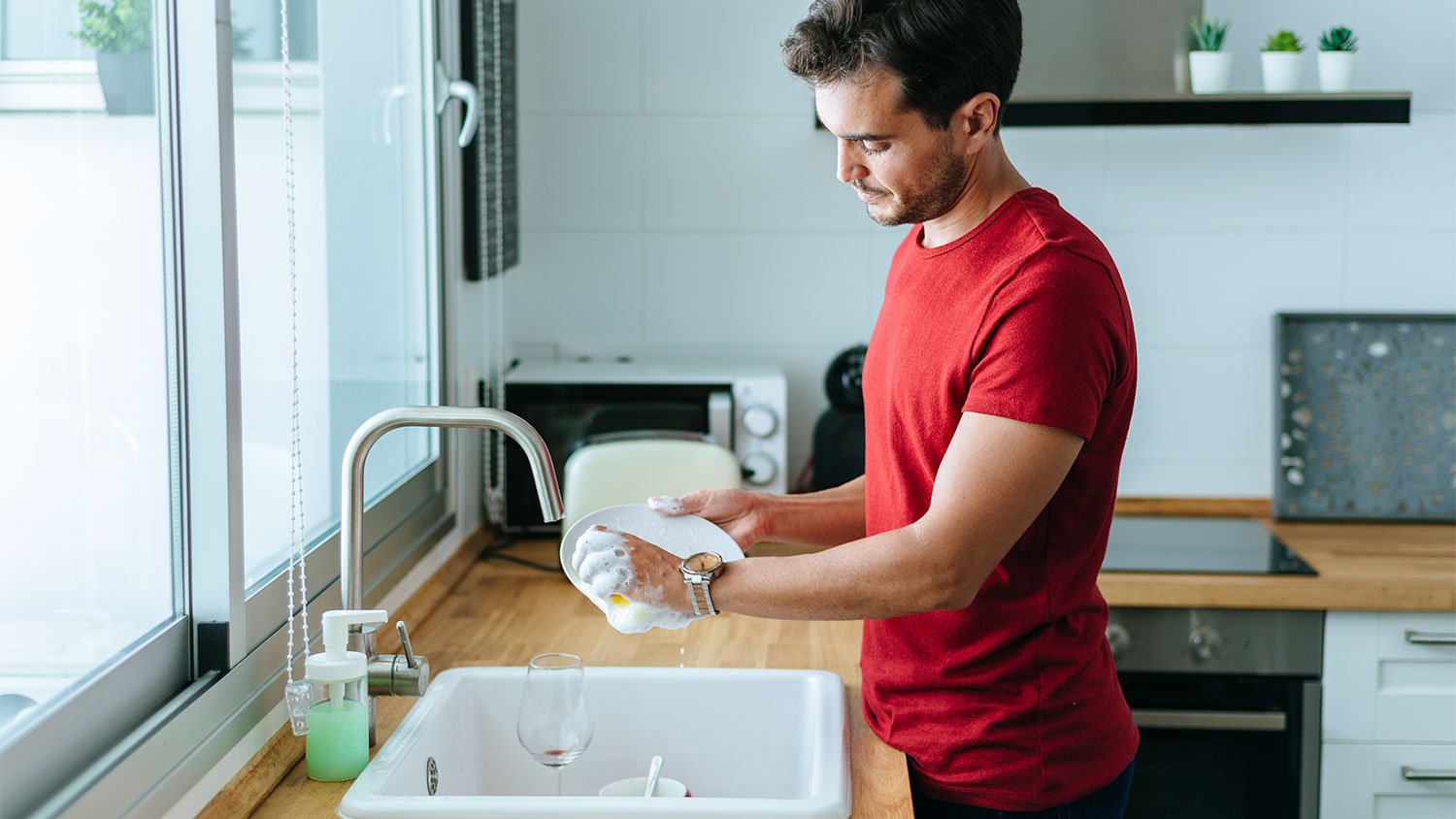 man washing dishes in kitchen