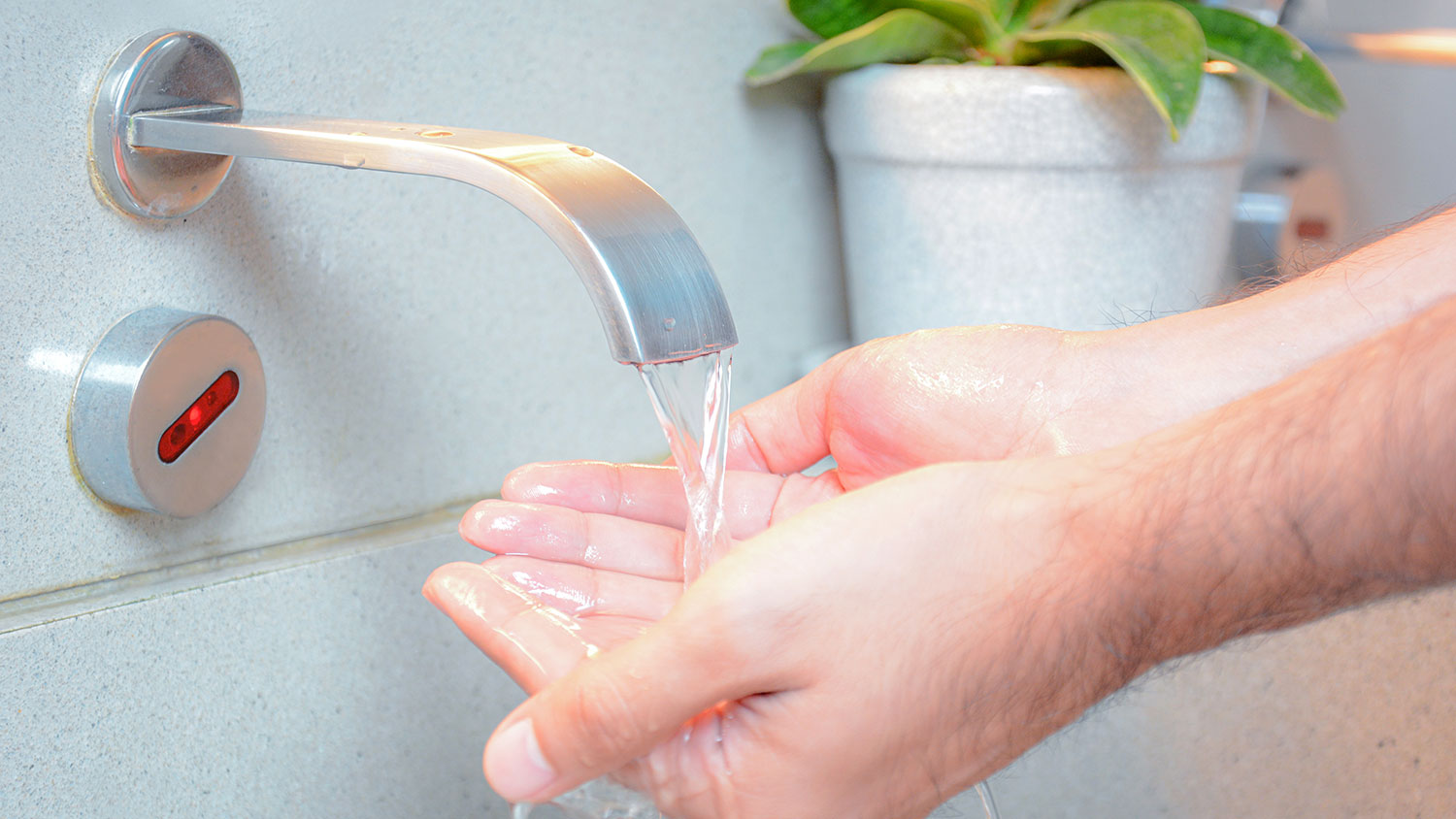 Man washing hands in motion sensor sink