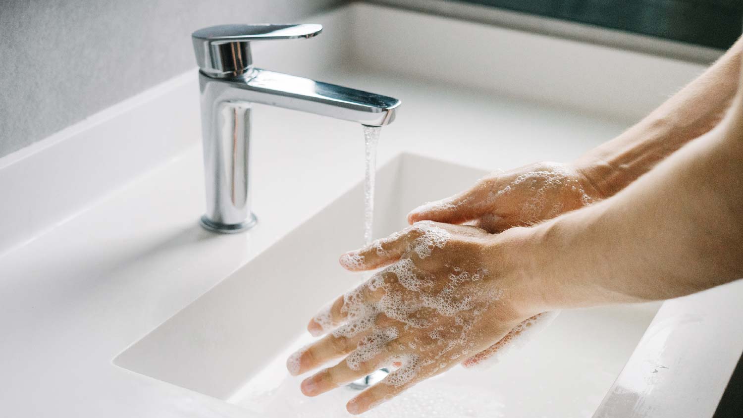 A man washing his hands in front of a single handle faucet