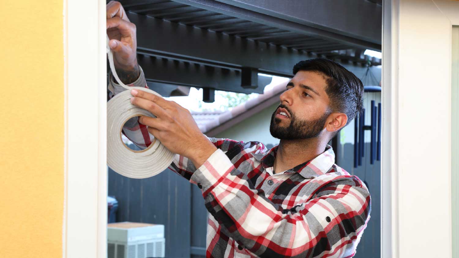 A man weather sealing a door