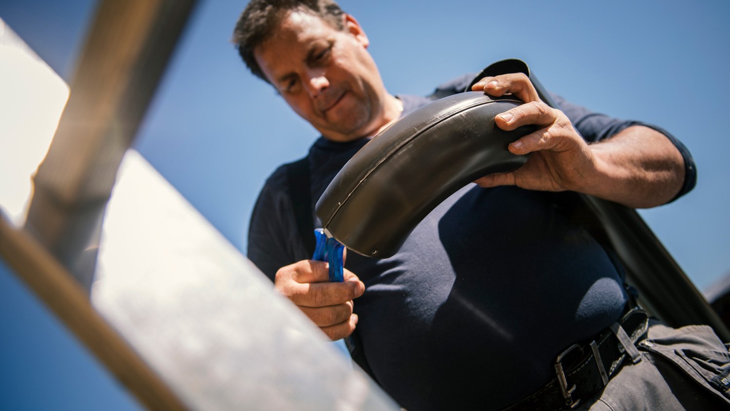 Roofer builder worker finishing folding a metal gutter