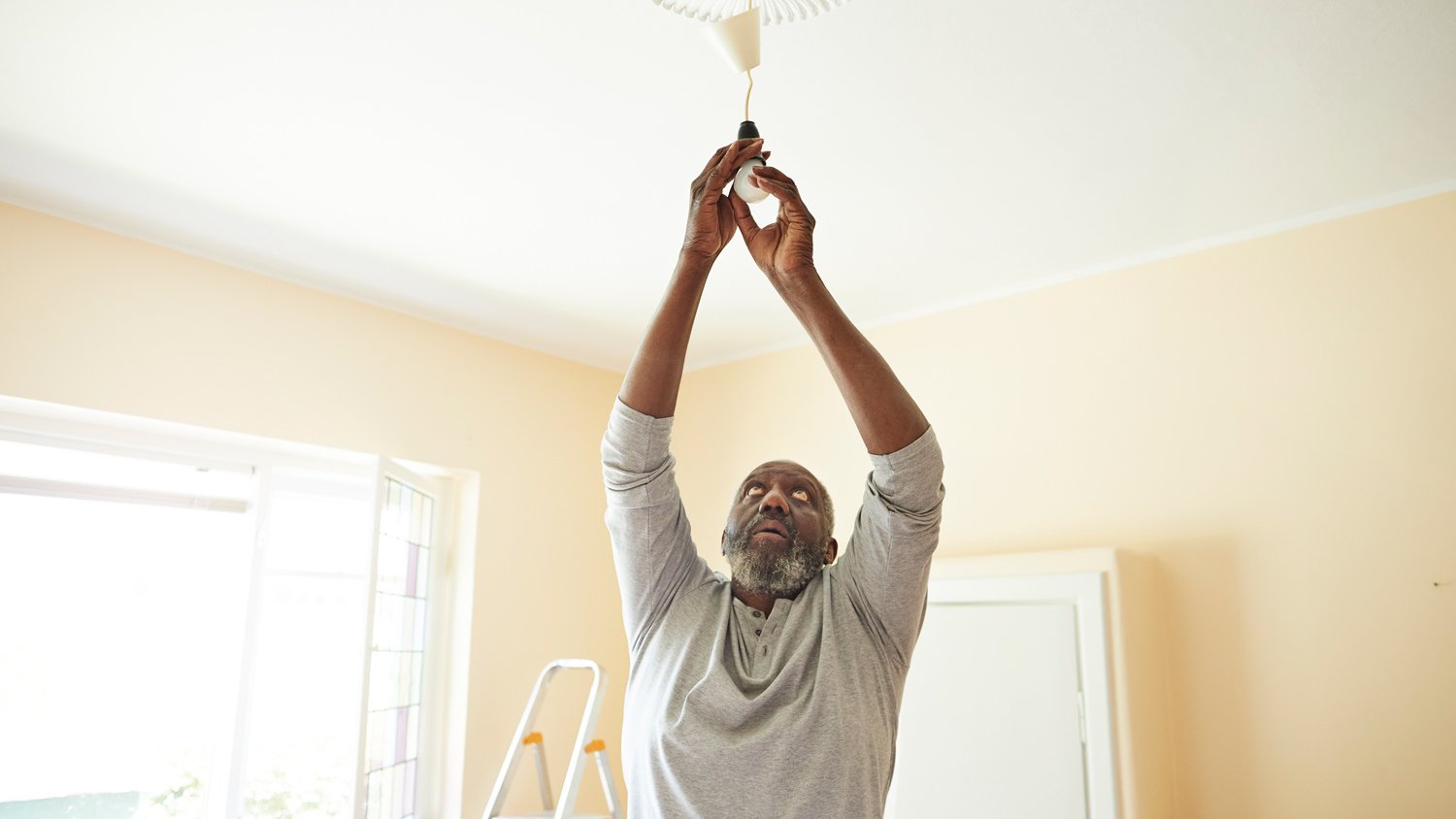 Man changing light bulb while renovating home