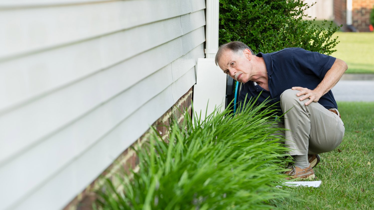 Home inspector with clipboard examines a home's brick foundation