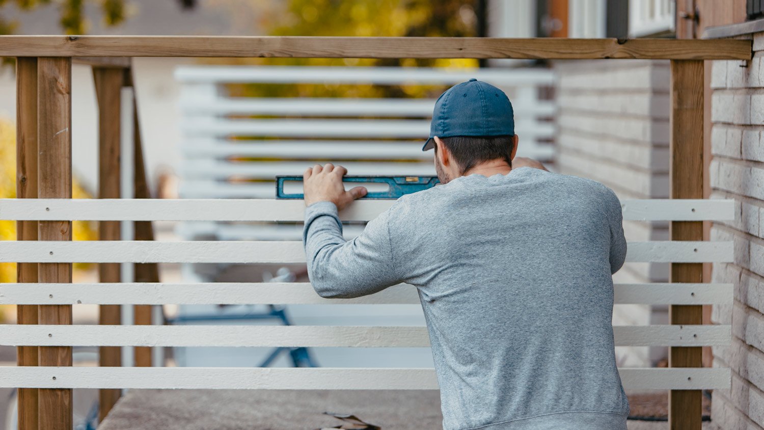 Carpenter using spirit level on patio railing