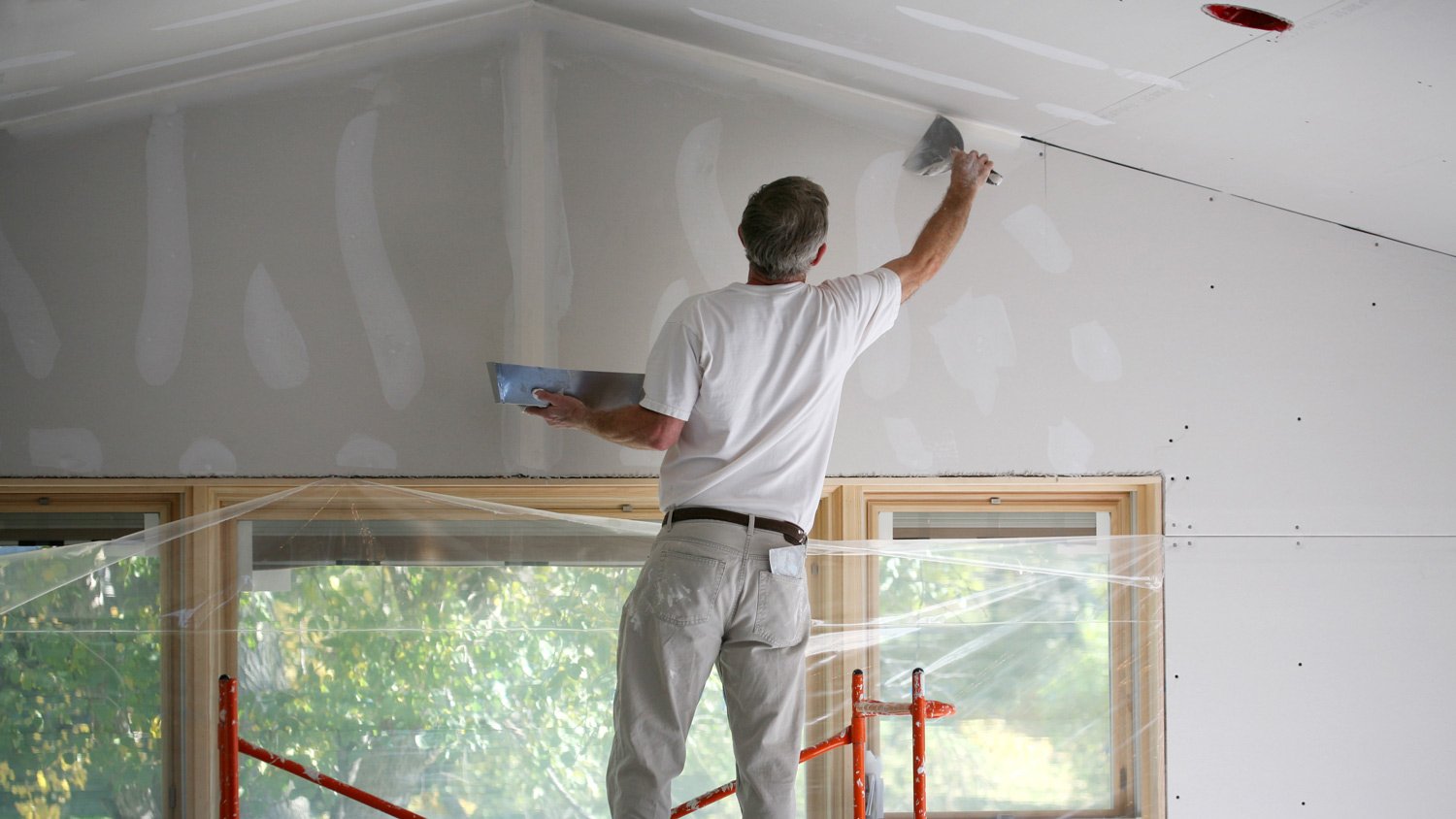 Man prepping wall for paint job