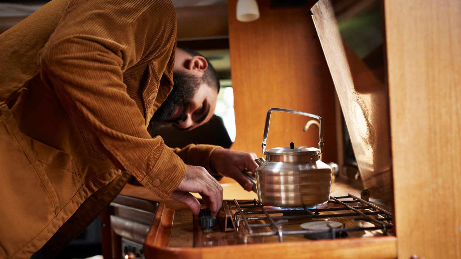 Mid adult man preparing food on stove in motor home