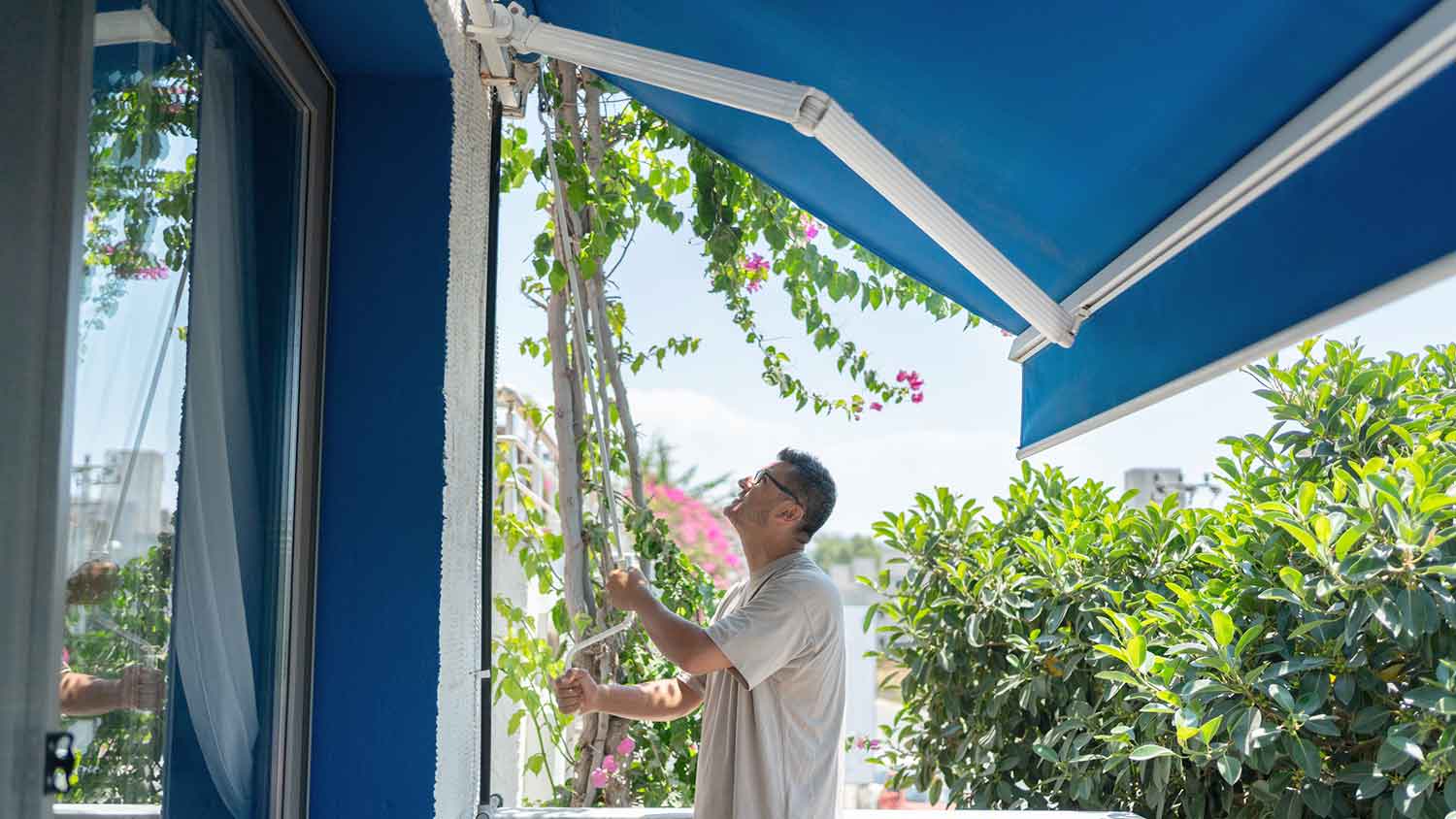 Man closing patio awning by hand