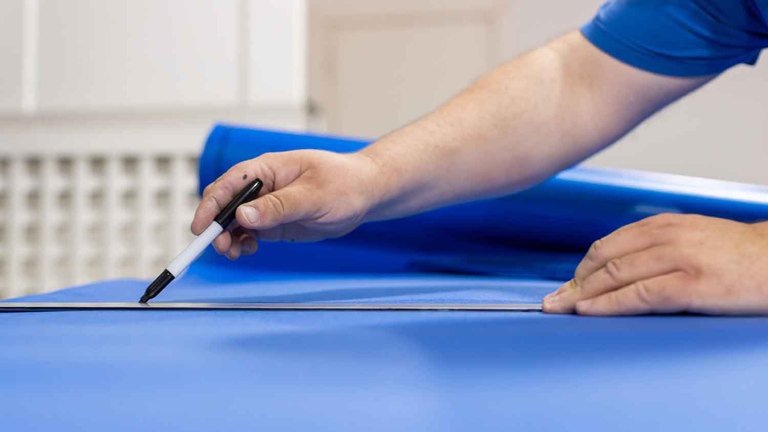 Man marking floor underlayment before cutting it