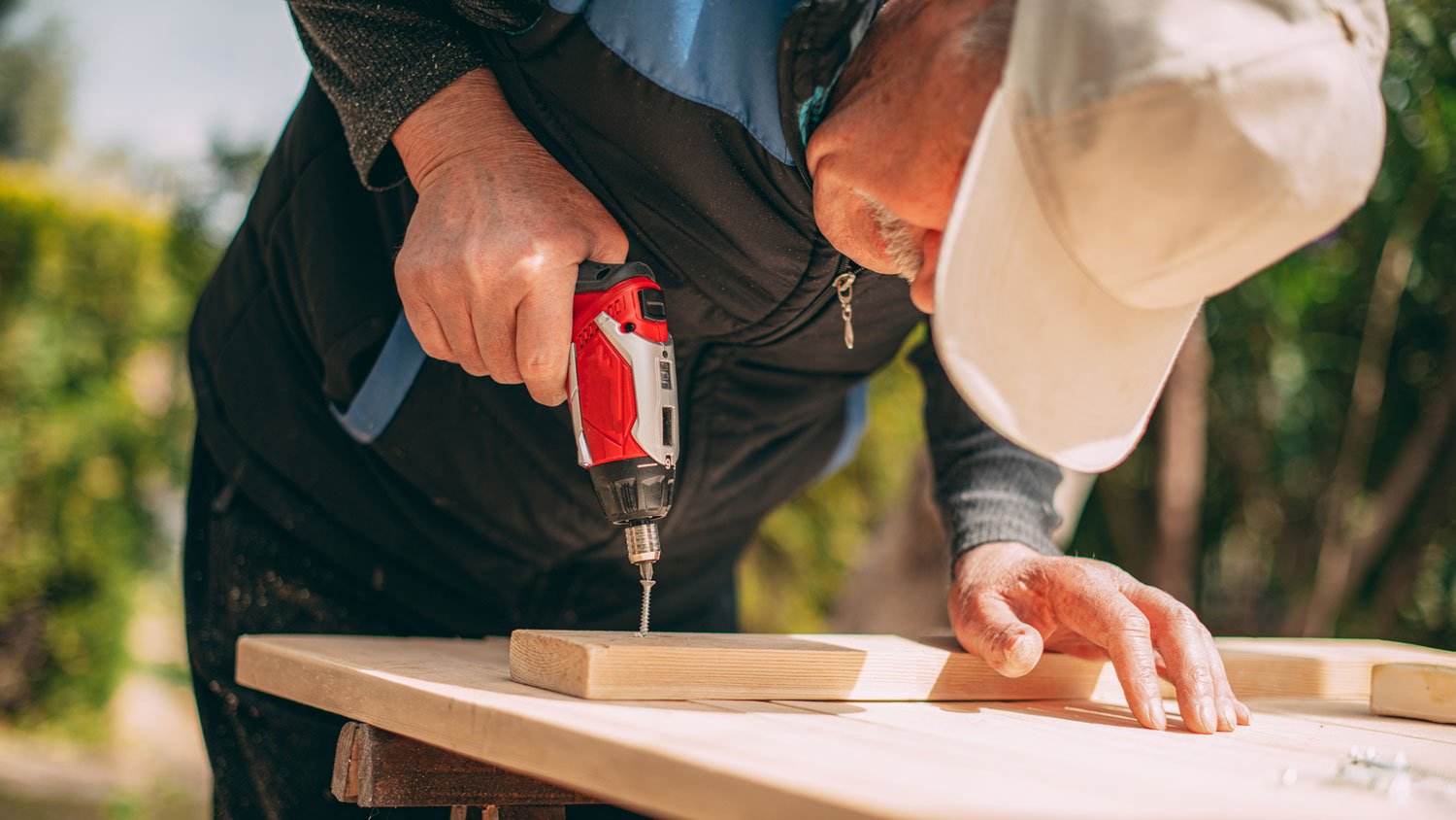 A mature man building a wooden fence