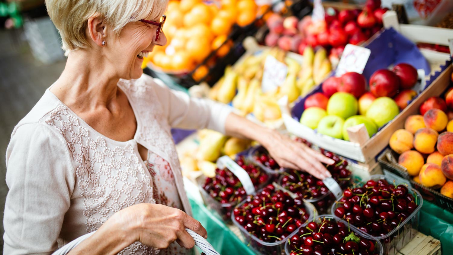 A mature woman buying vegetables from a local farmer’s market