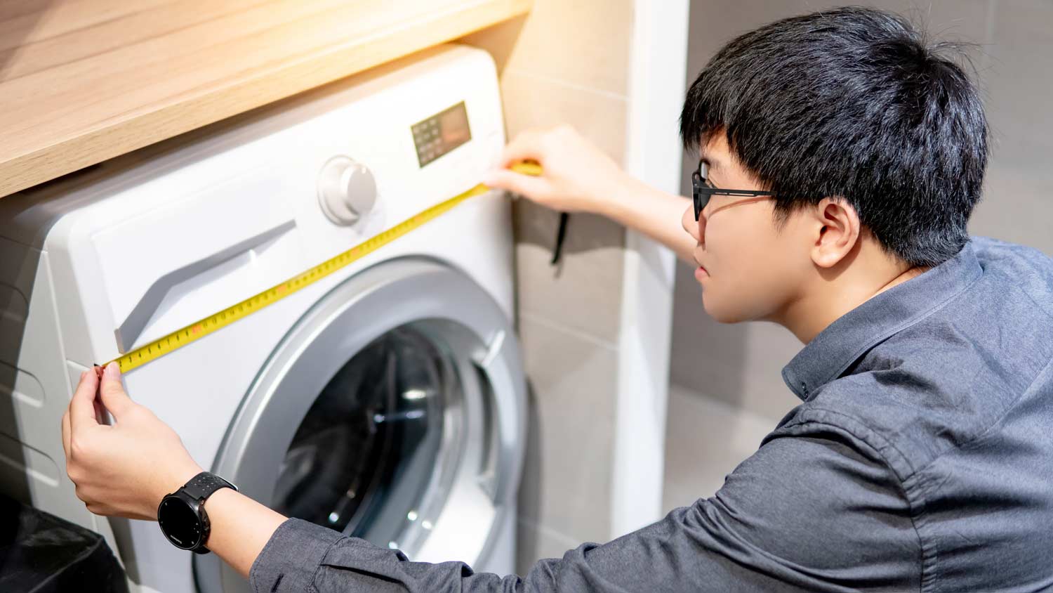 man measuring width of washer machine 