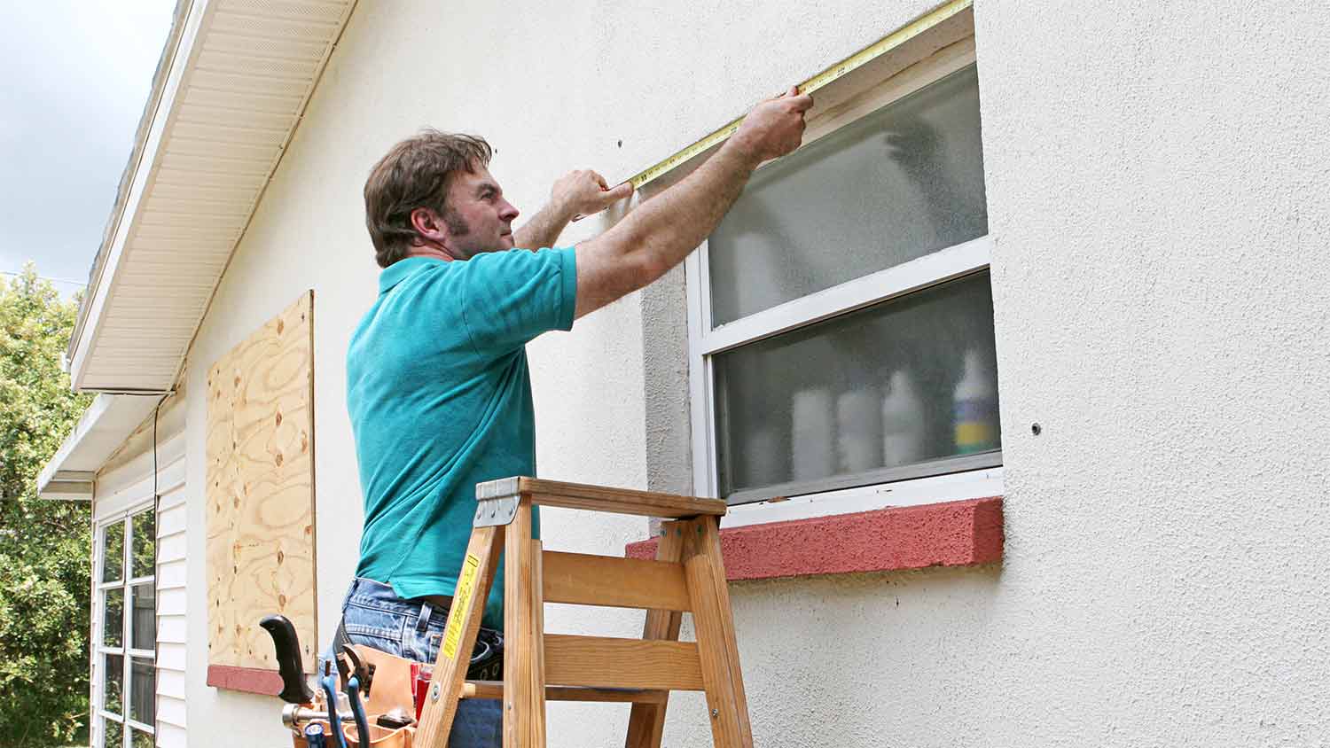man measuring window for hurricane shutters