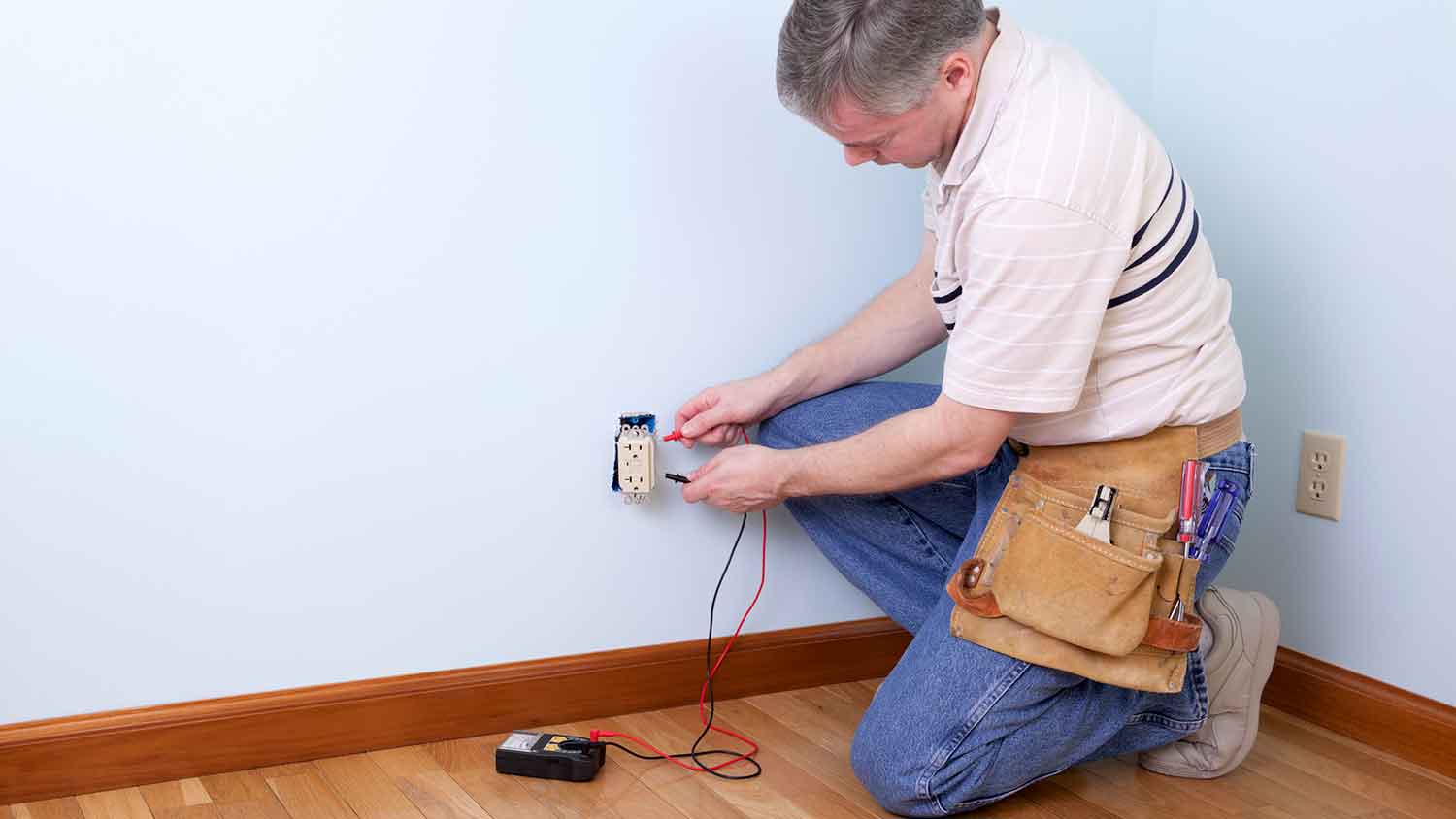 Electrician using multimeter to measure outlet voltage