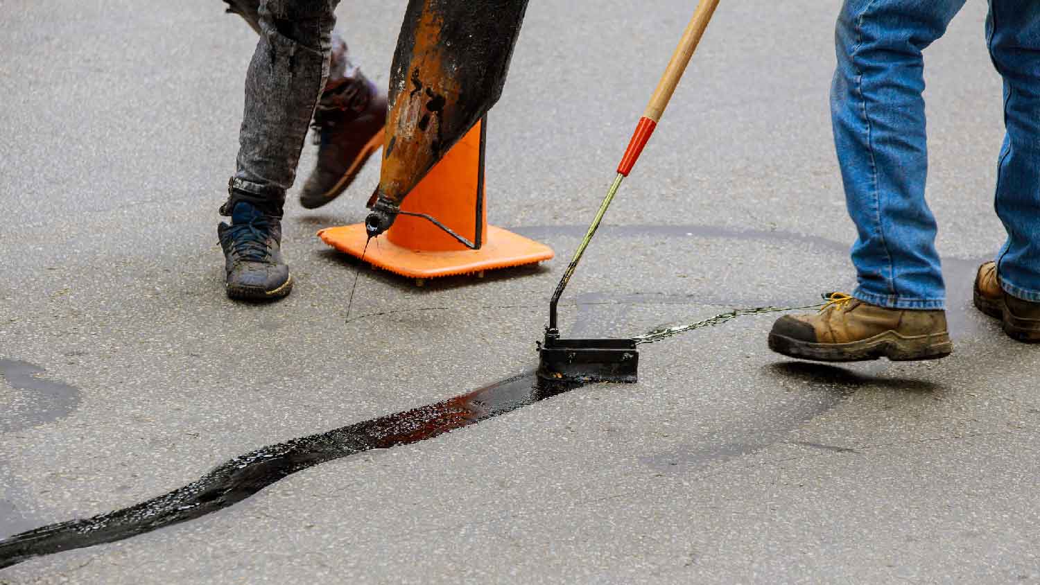 Two men crack sealing a concrete slab