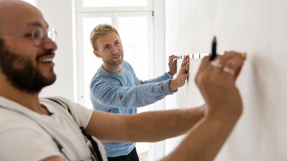 Two men taking measurements using a measuring tape