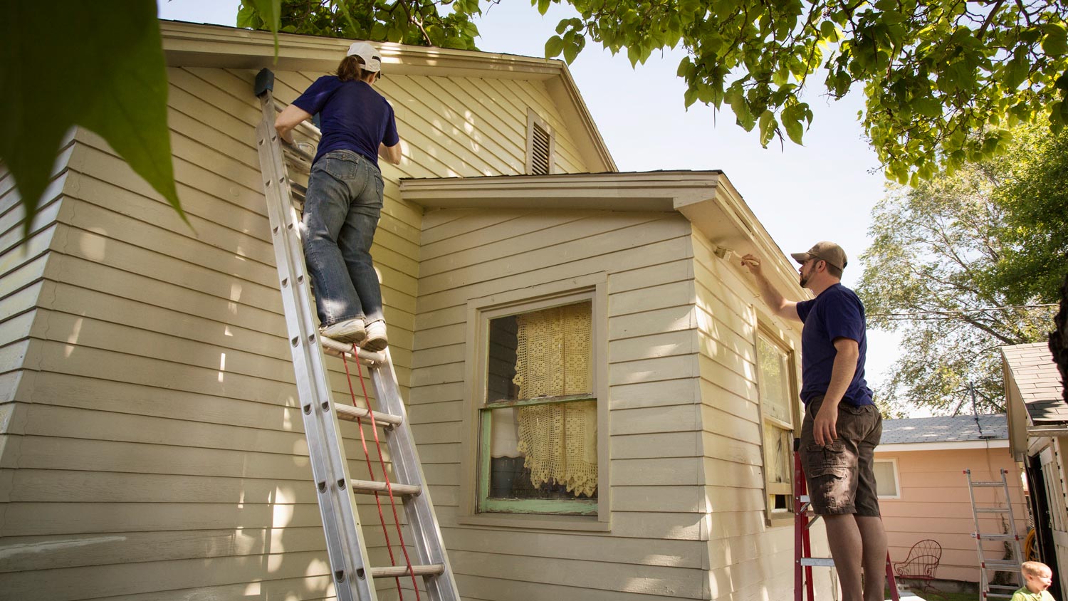 2 men painting outside of house