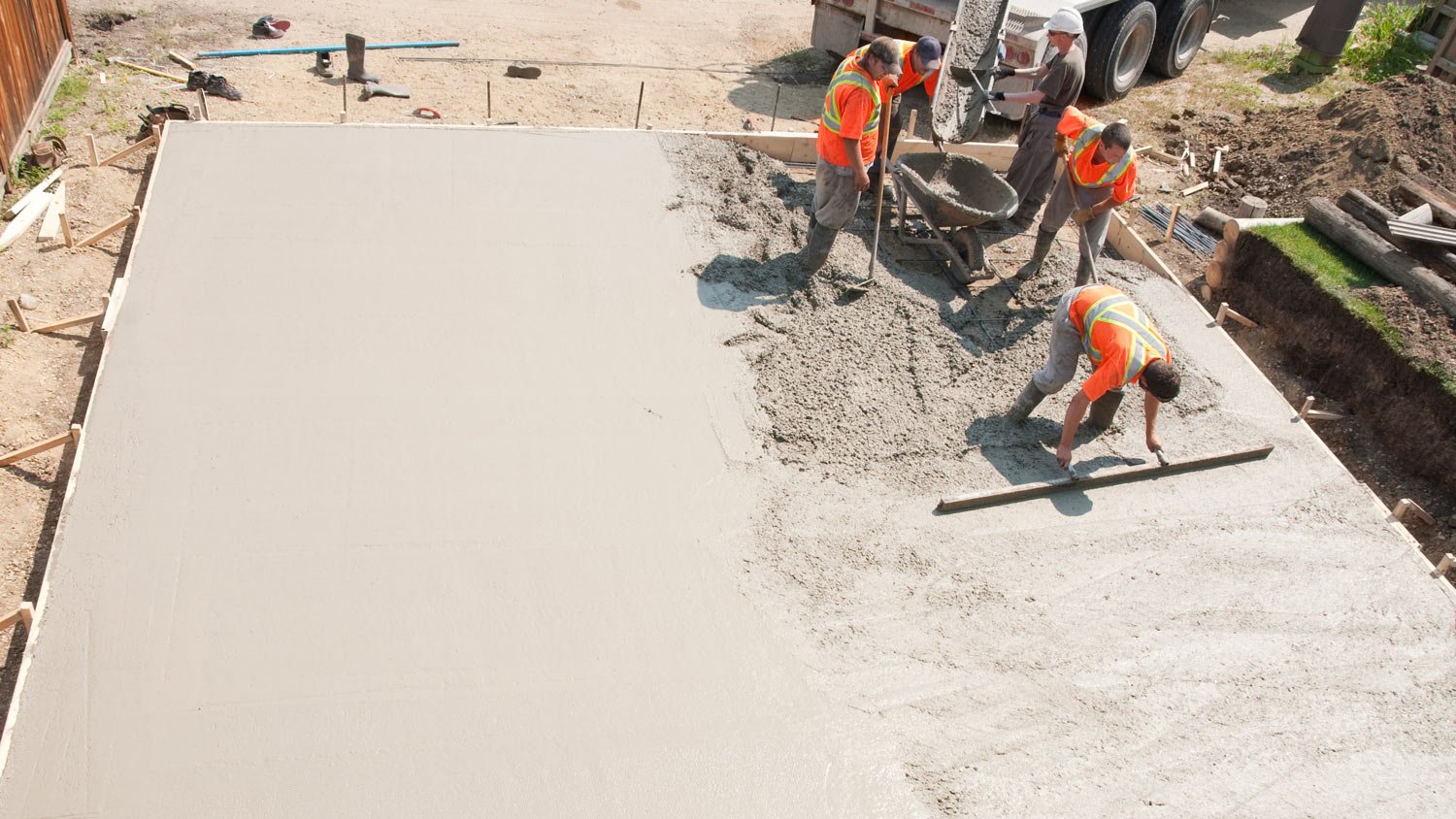 Crew of concrete workers pouring and leveling a garage pad