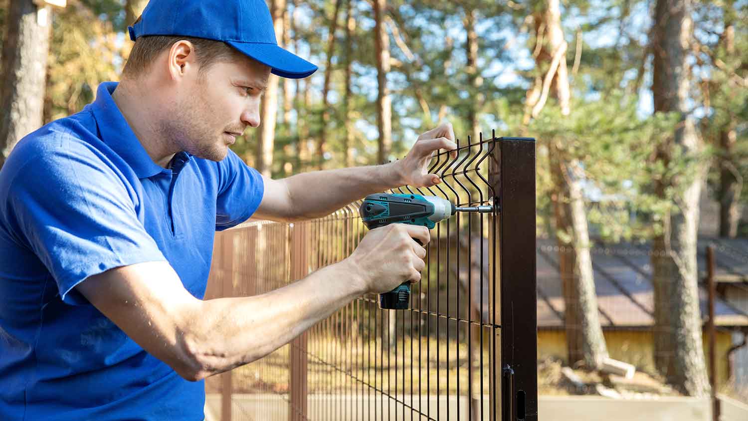 Worker installing new metal fence