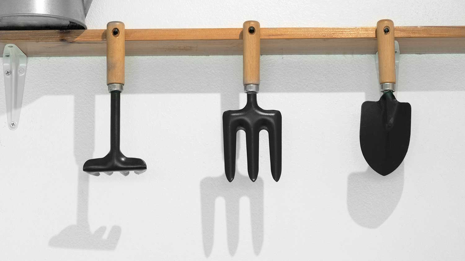 Metal gardening tools hanging on the shelf