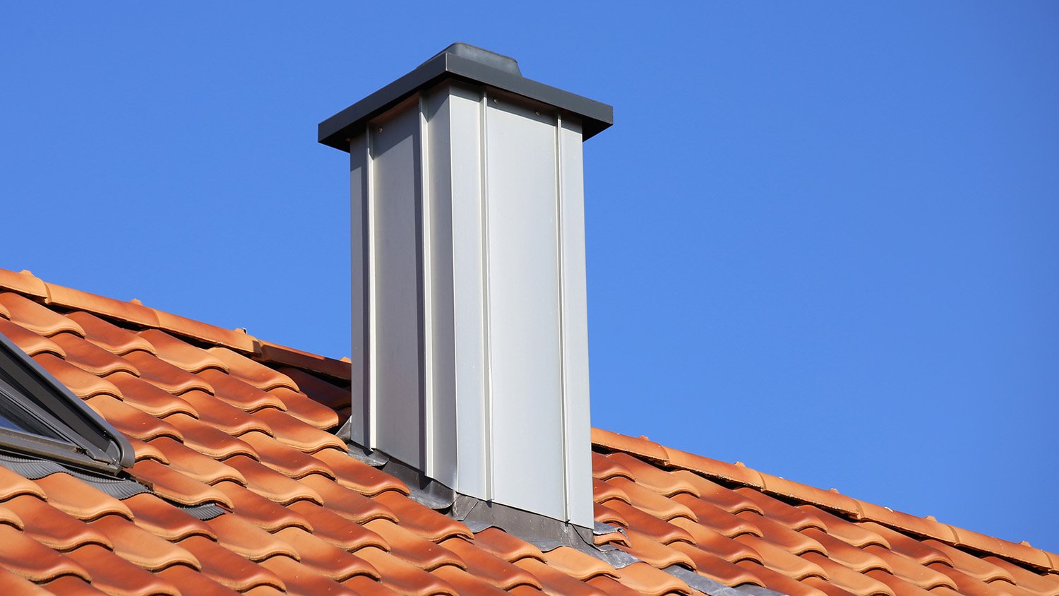 Roof of a house with a metal sheeting chimney