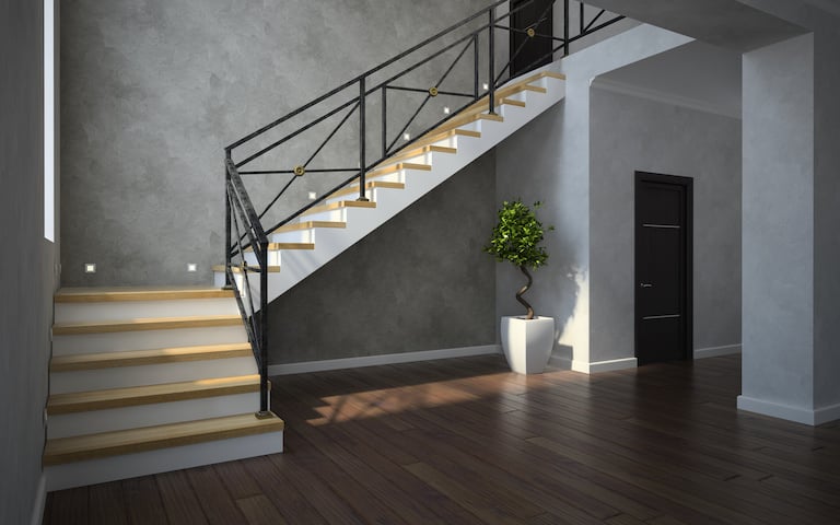 a black metal staircase leads to the upstairs area, with gray walls, dark brown wood floors, and a plant