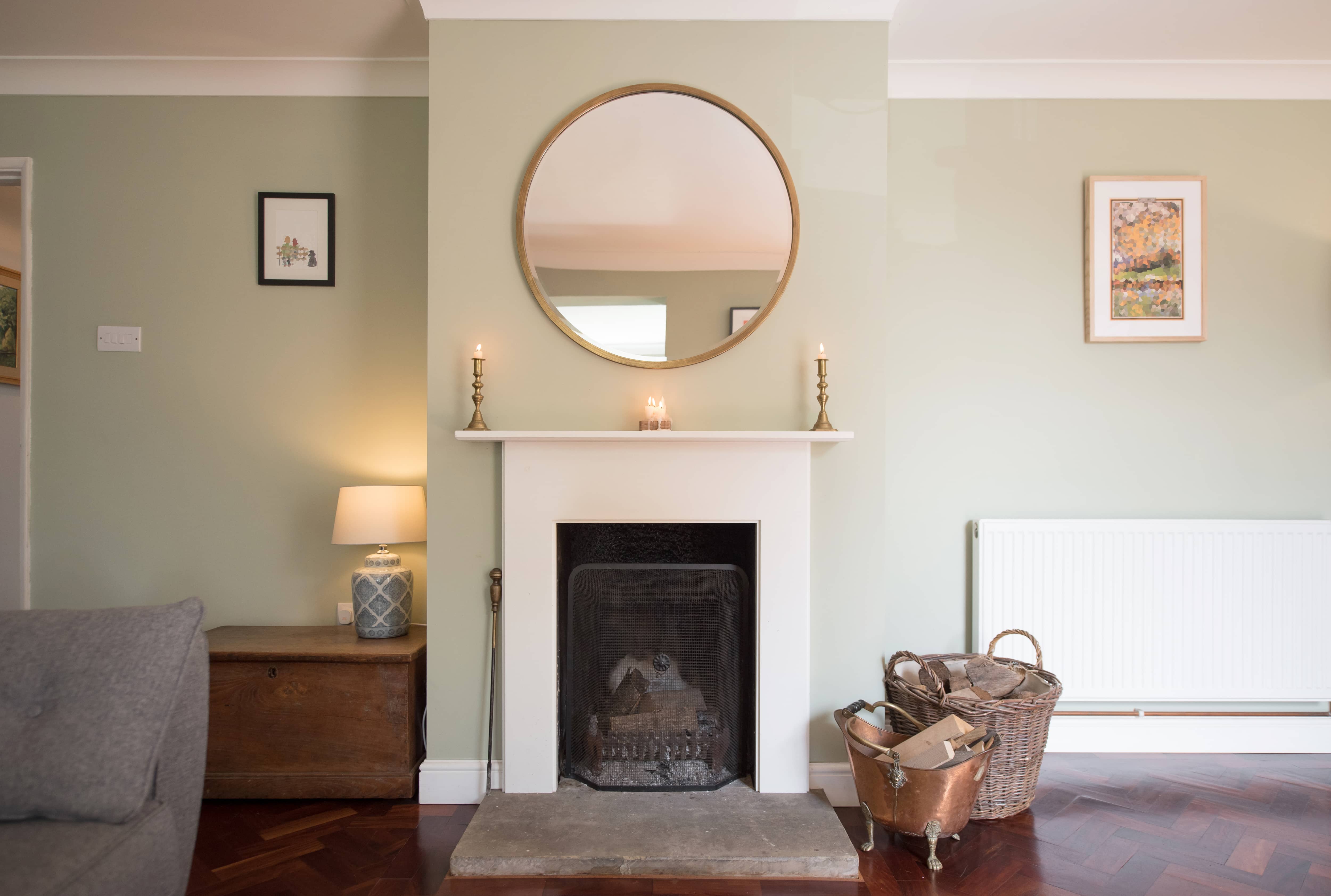 White fireplace in seafoam green living room with stone hearth and antique metal decor