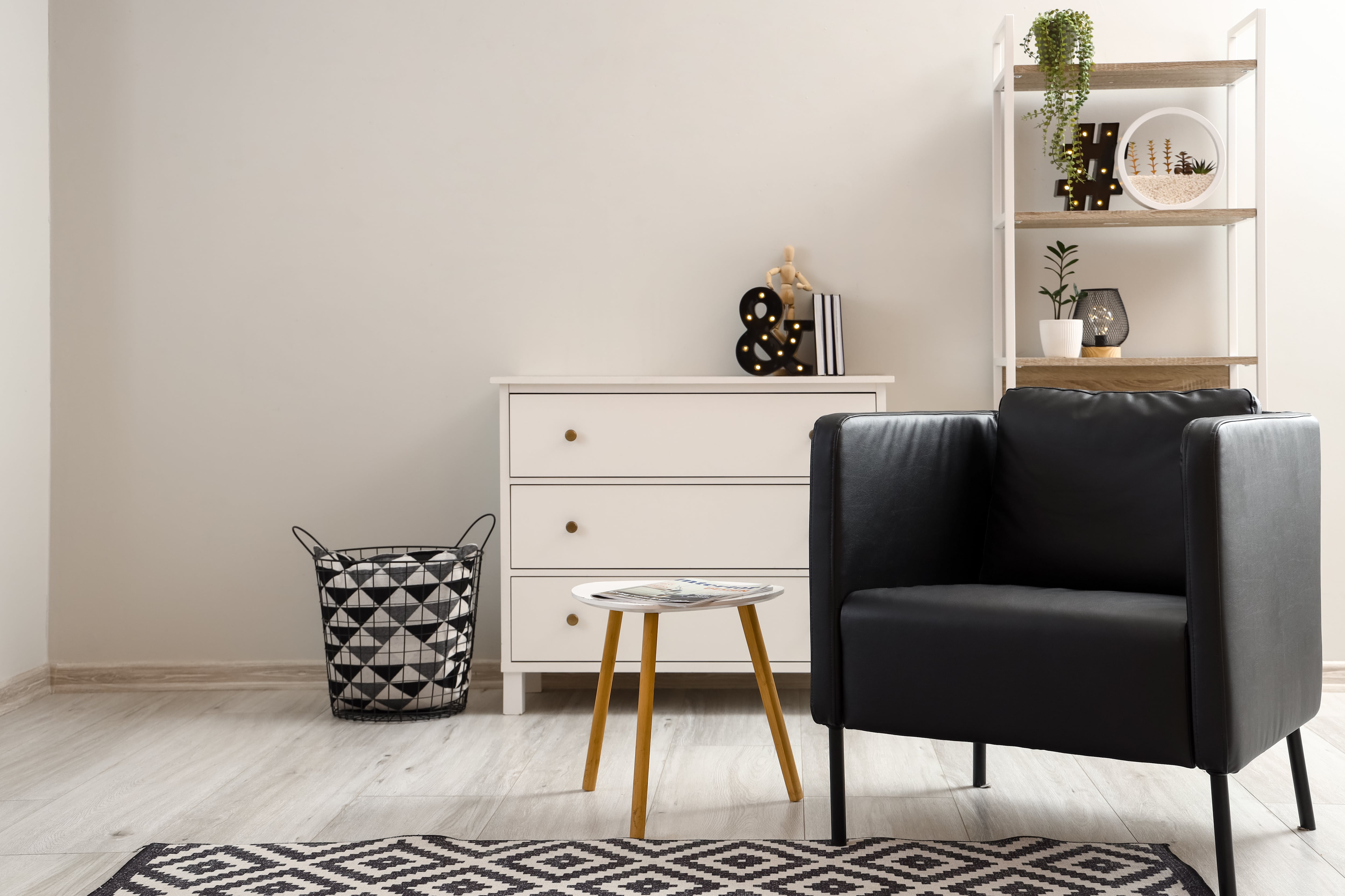 Black leather armchair in a sunny living room with a black and white rug and white coffee table