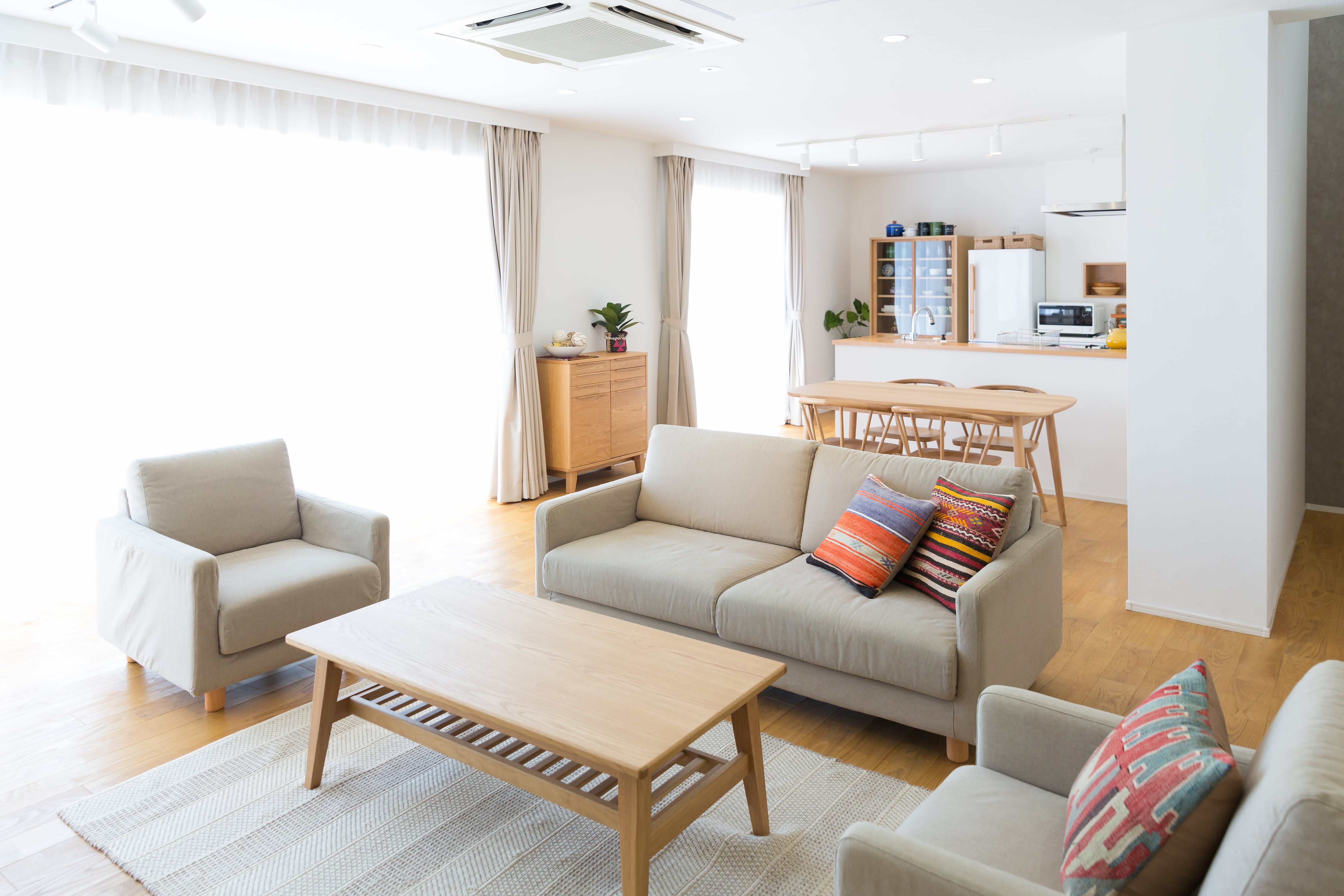 Bright, minimalist modern living room with matching sofa and armchairs and coffee table. 