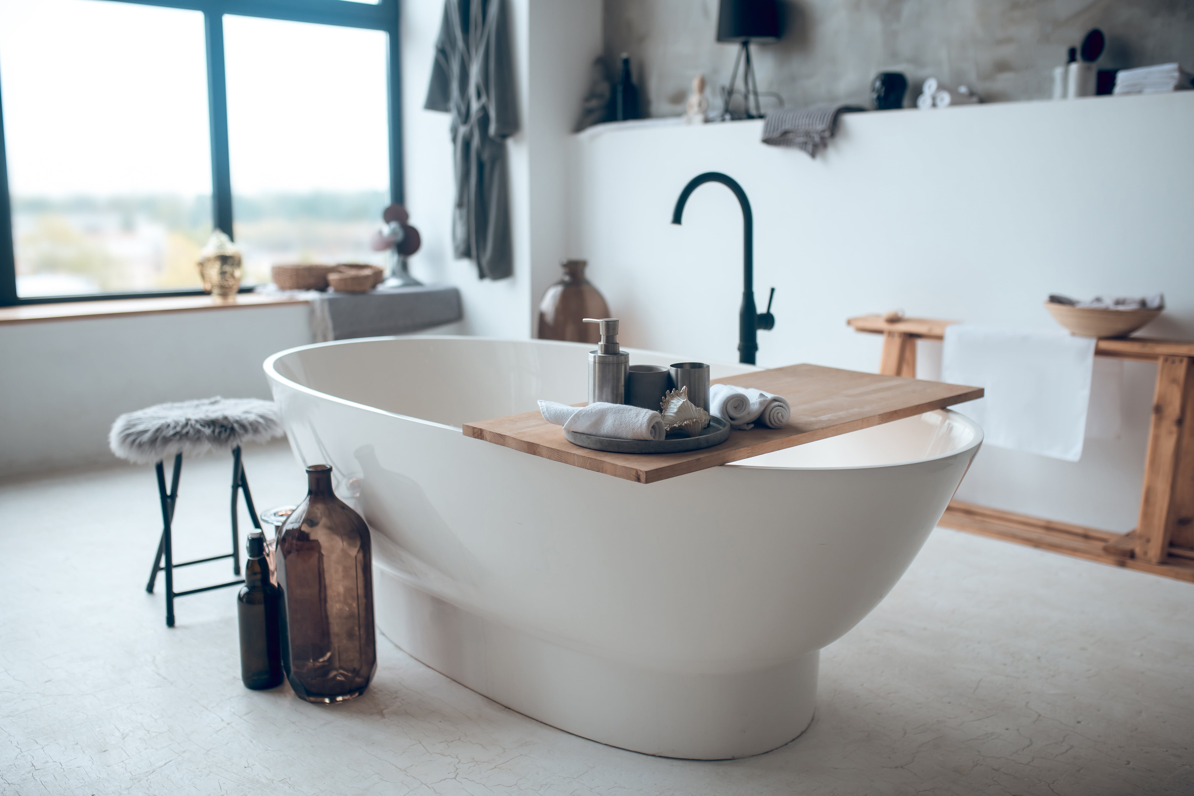 Modern bathroom with freestanding tub and wooden bathtub caddy