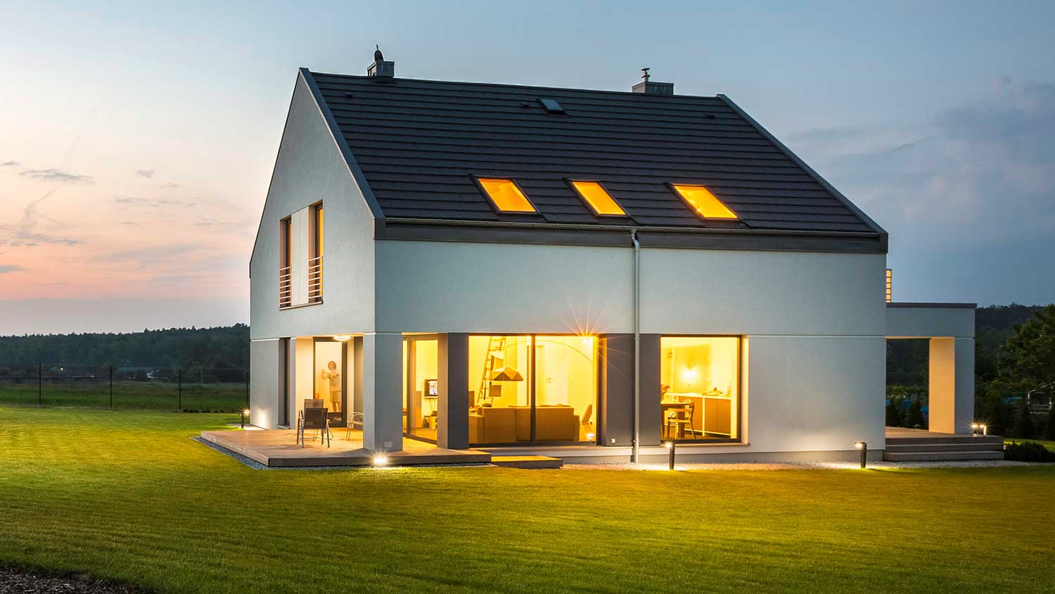 Modern country house with lights on at night 