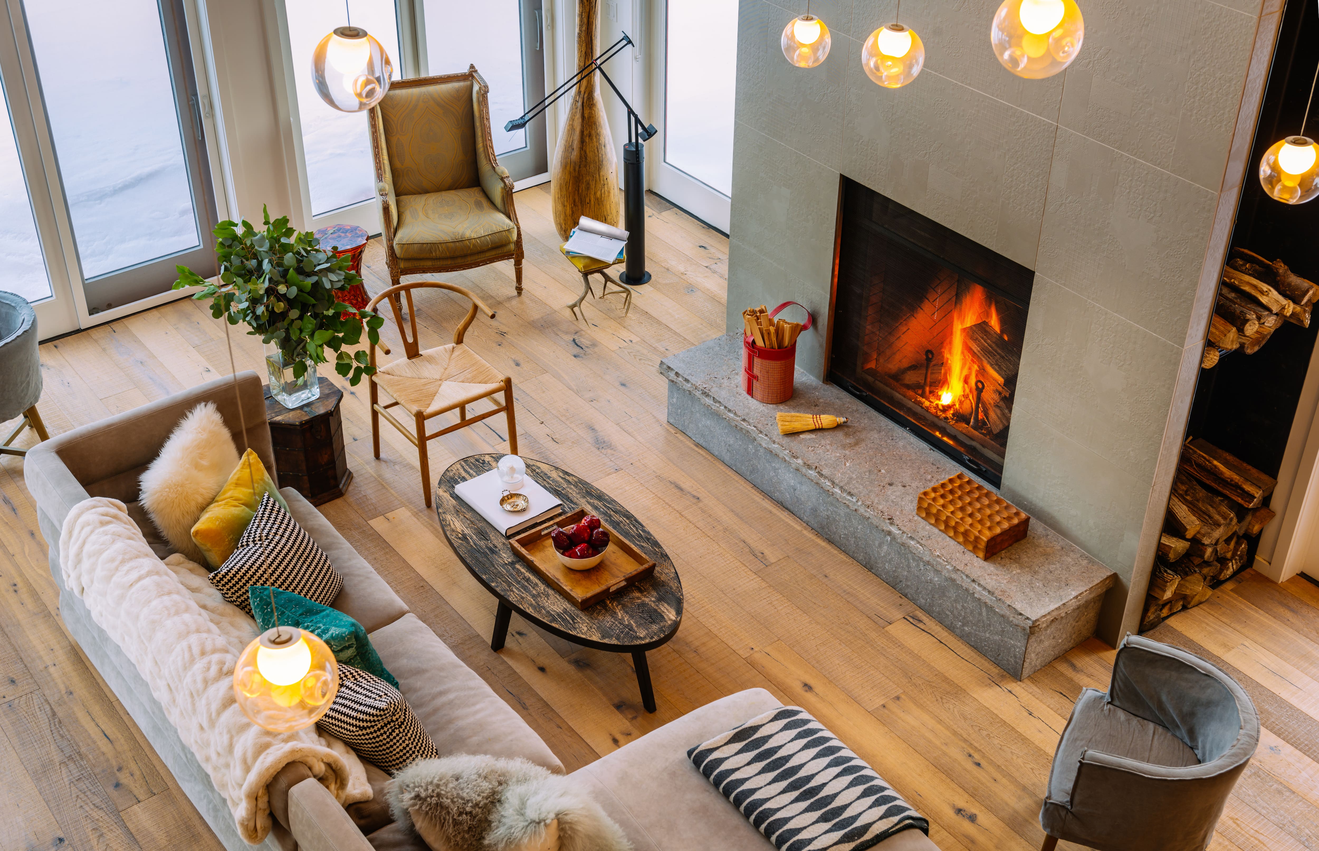 Modern room with grand stone and concrete fireplace, hardwood floors, and cozy furniture