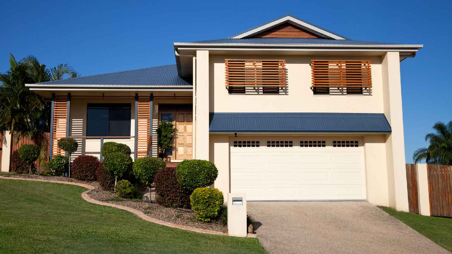 A modern home with a driveway and lanscaped gardens