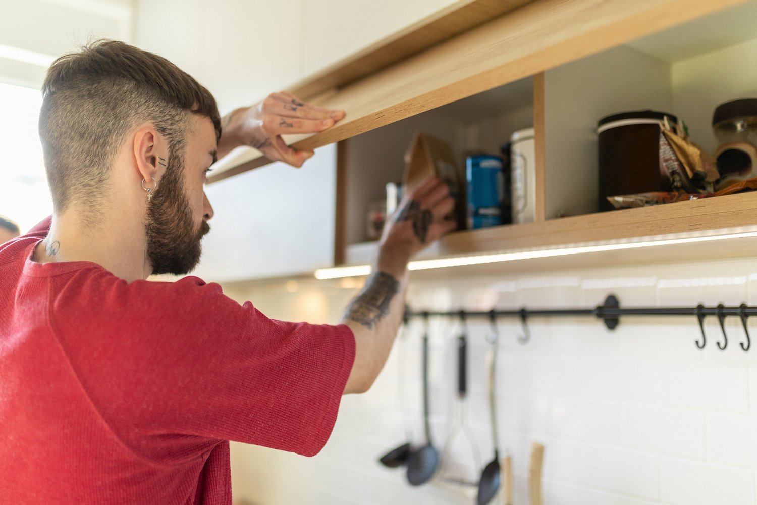 A young man grabbing a paper bag from a kitchen cabinet