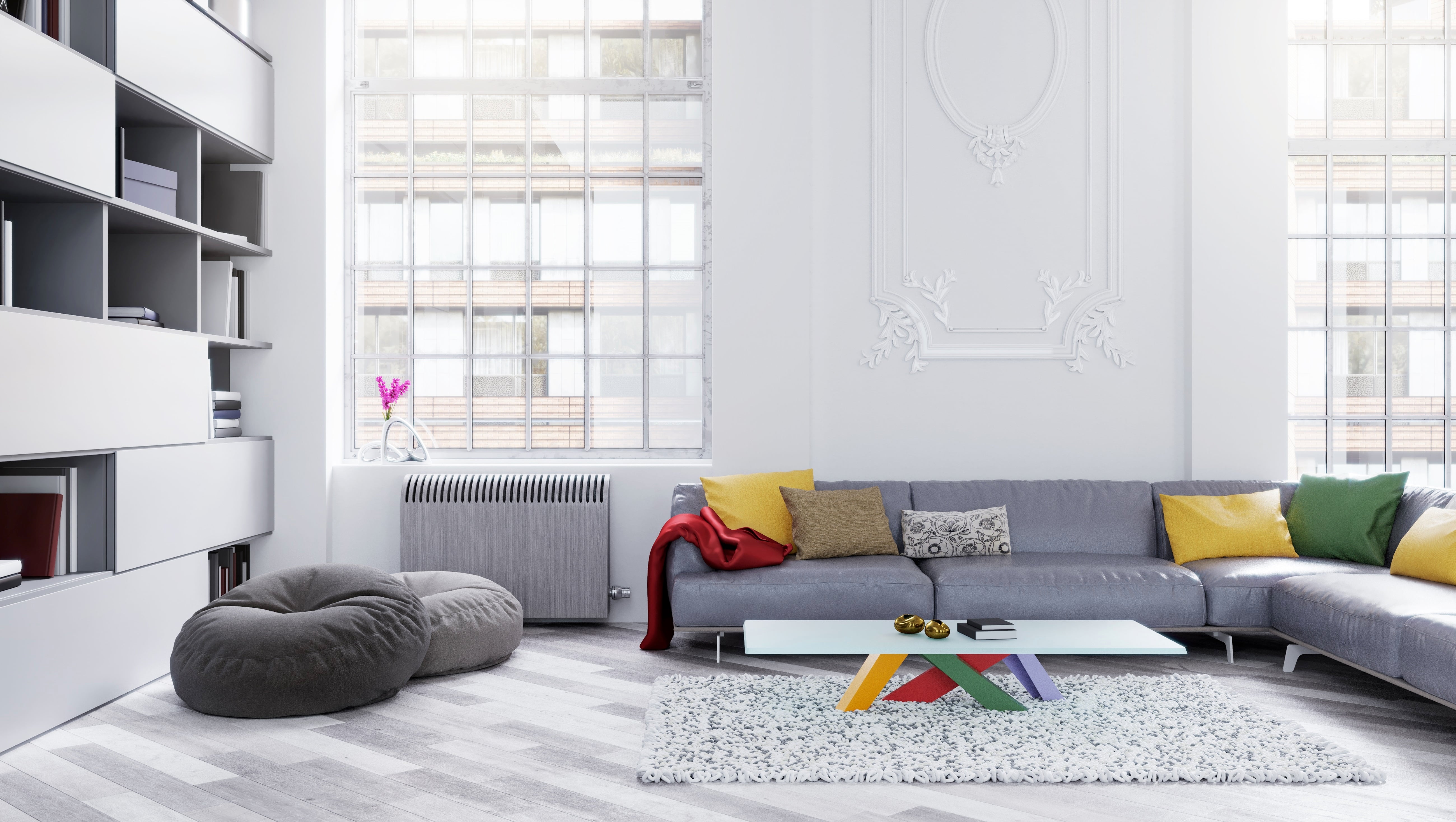 A gray-and-white living room with colorful pillows and coffee table