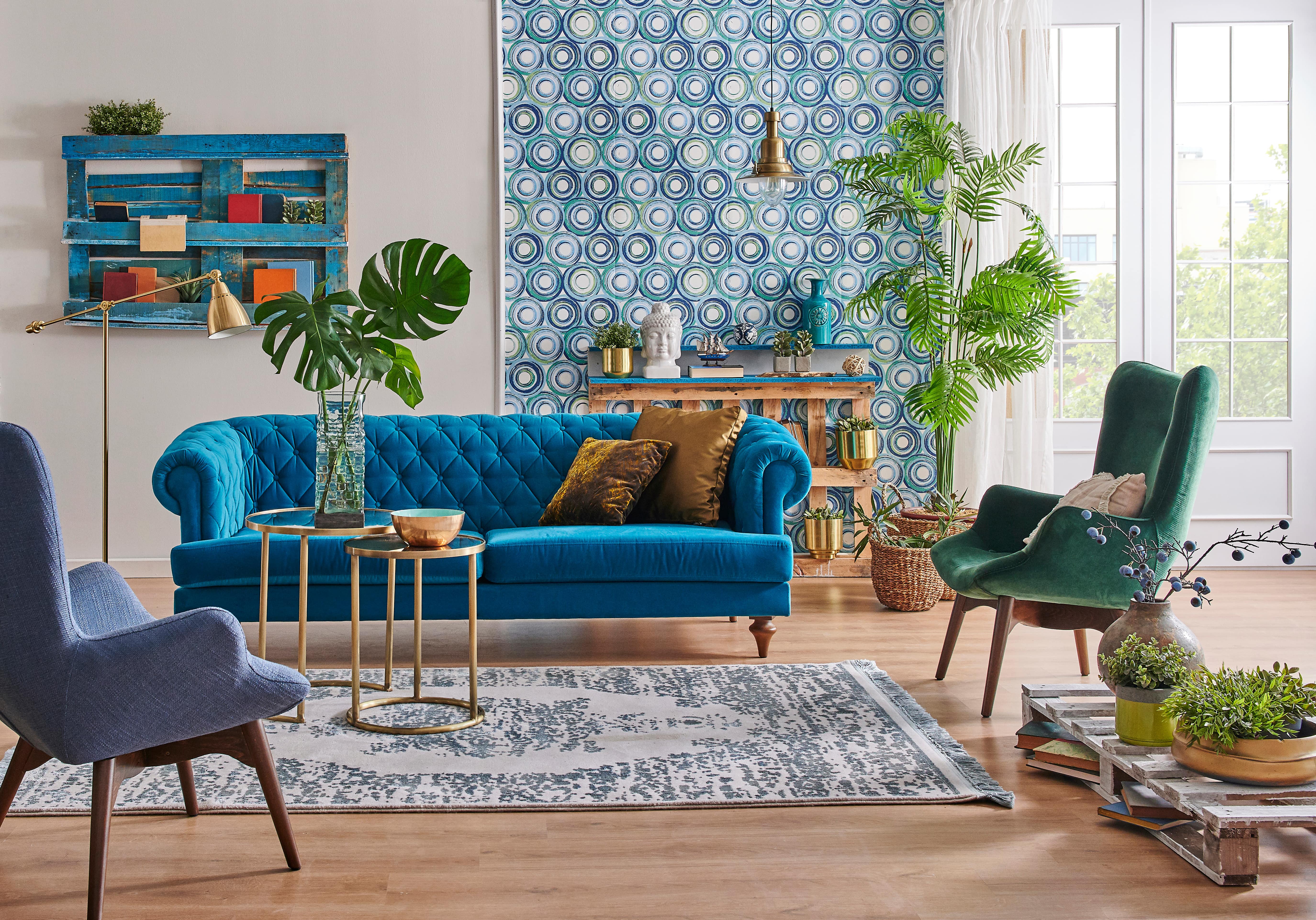 A living room with a blue-and-green statement wall and jewel-toned furniture