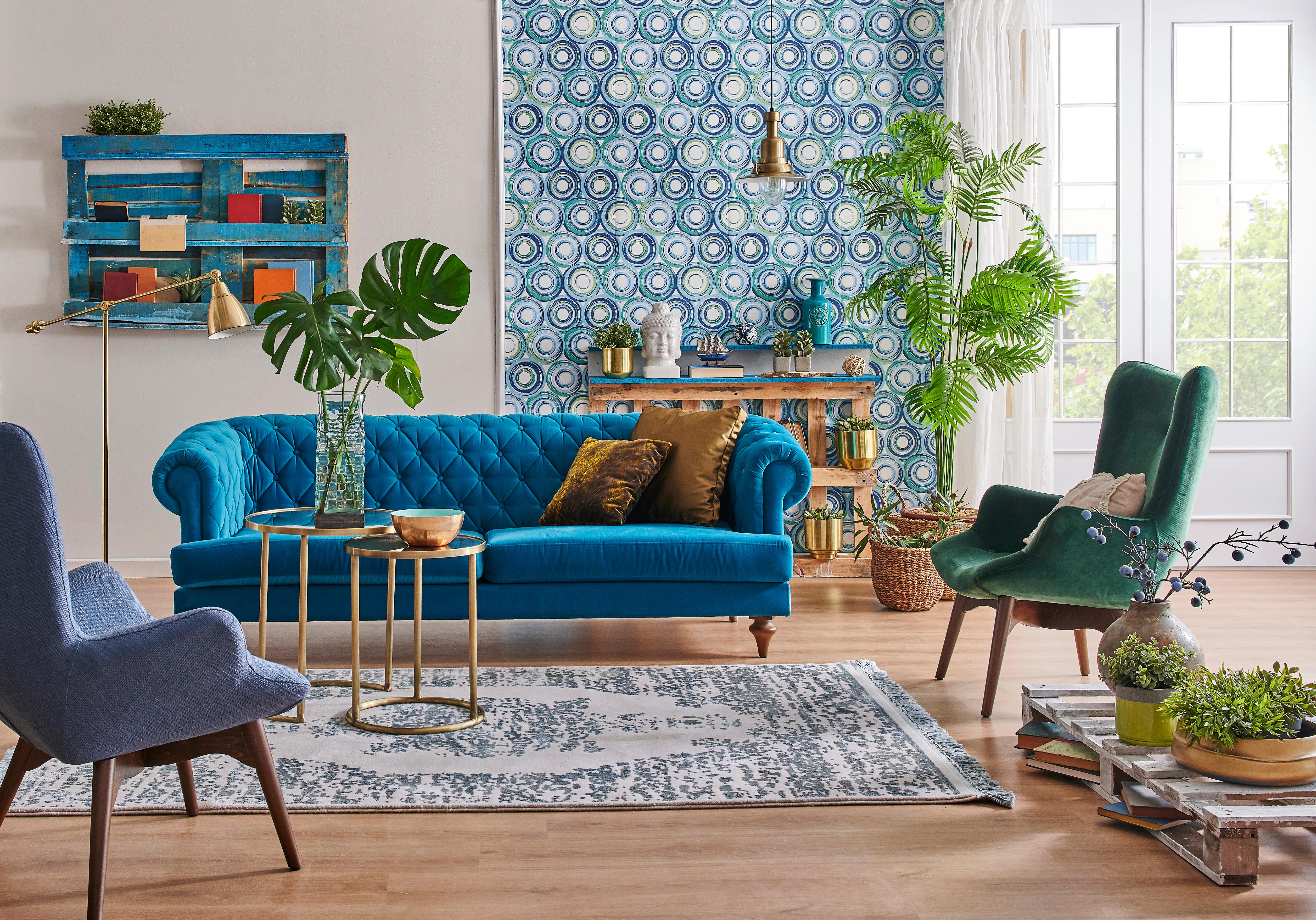  A living room with a blue-and-green statement wall and jewel-toned furniture