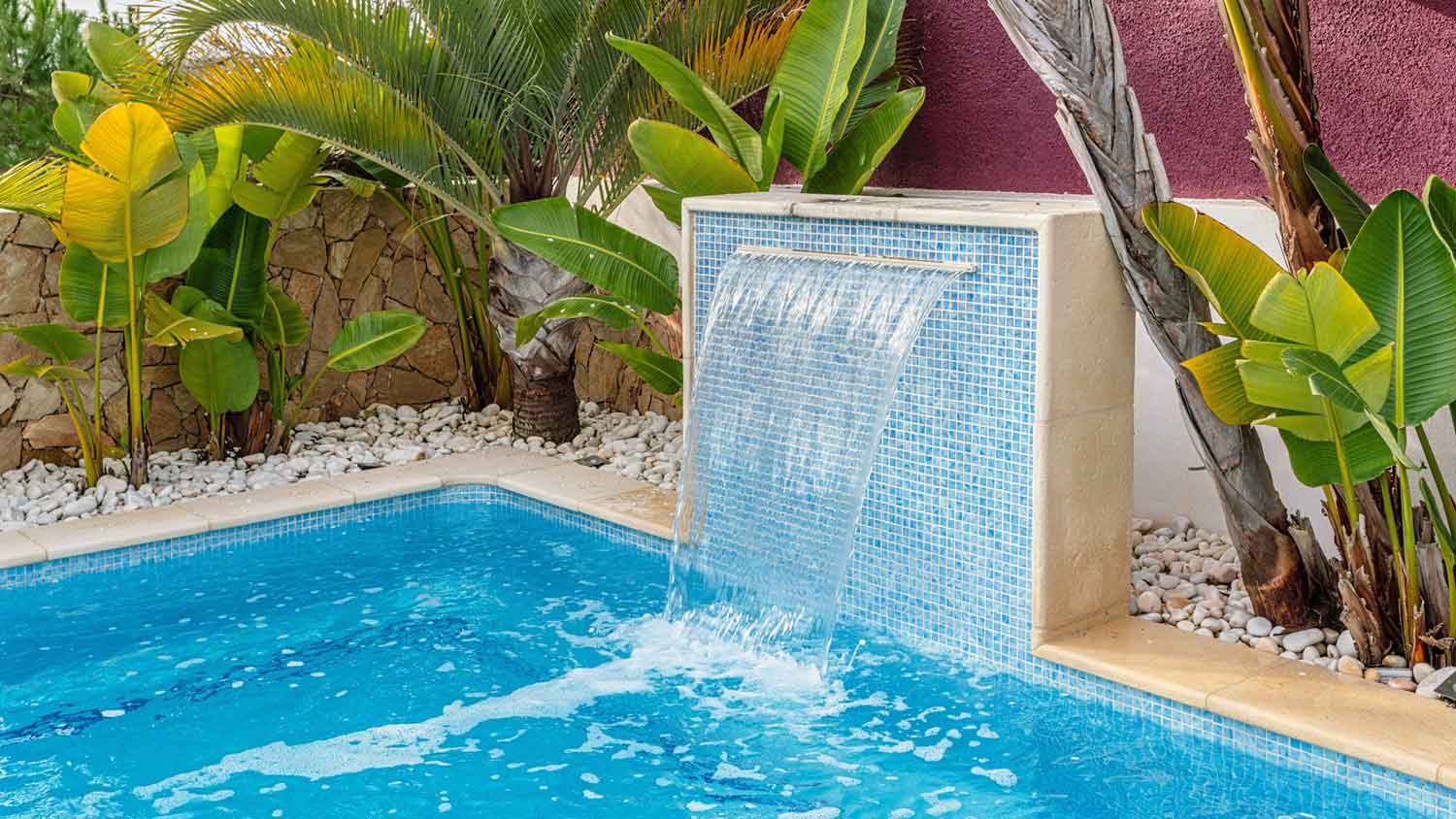 Swimming pool with modern waterfall and plants