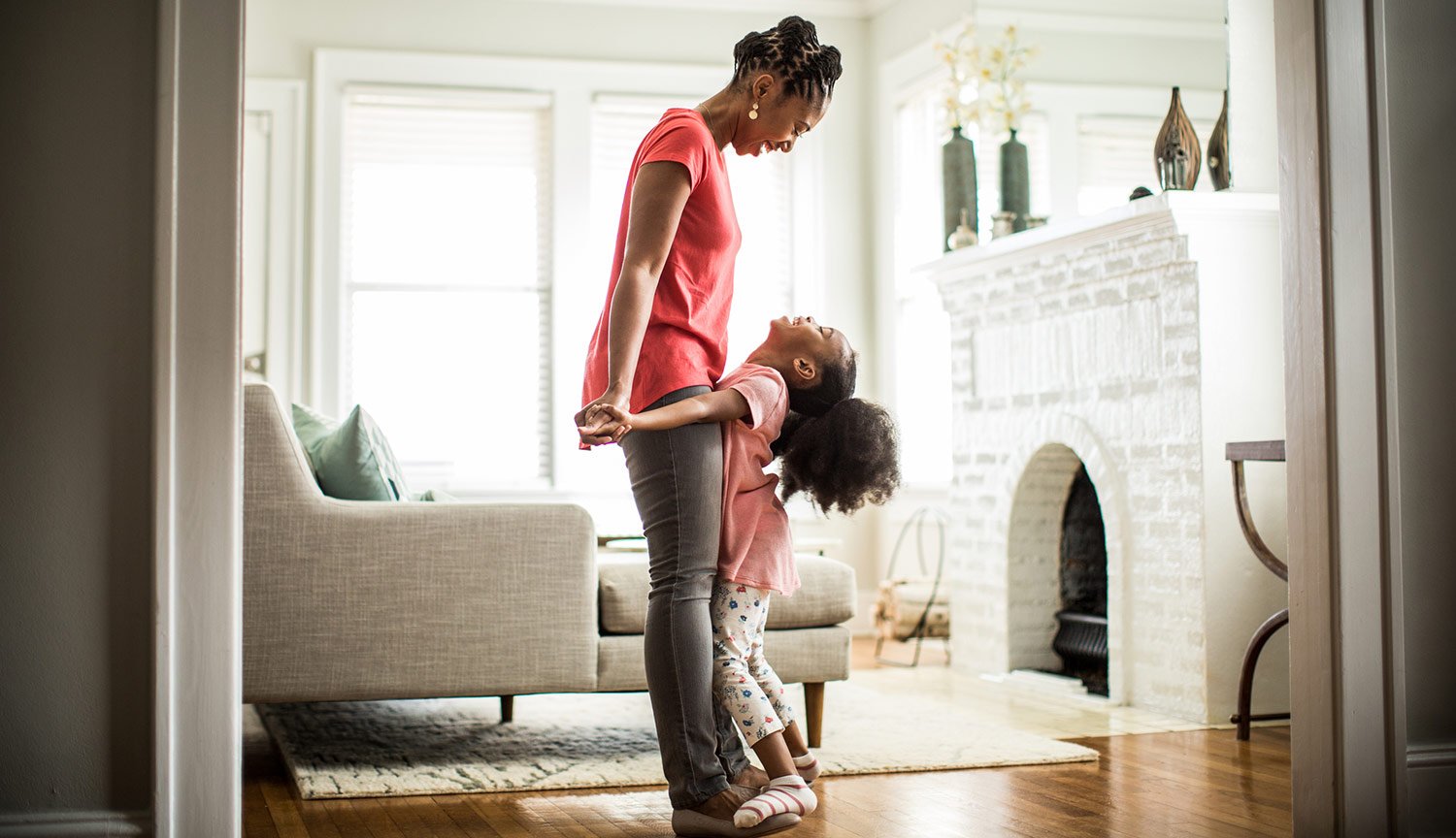 Daughter dancing on mom's feet in living room