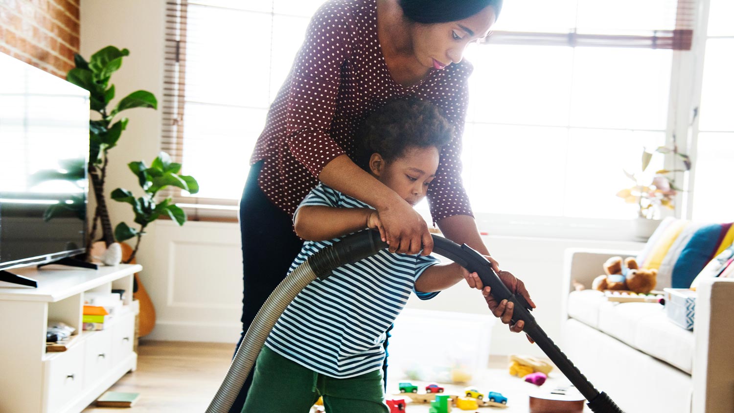 A mom and her son vacuuming the living room