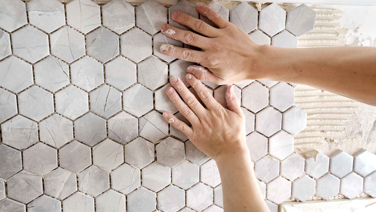 Worker installing new mosaic tile sheet