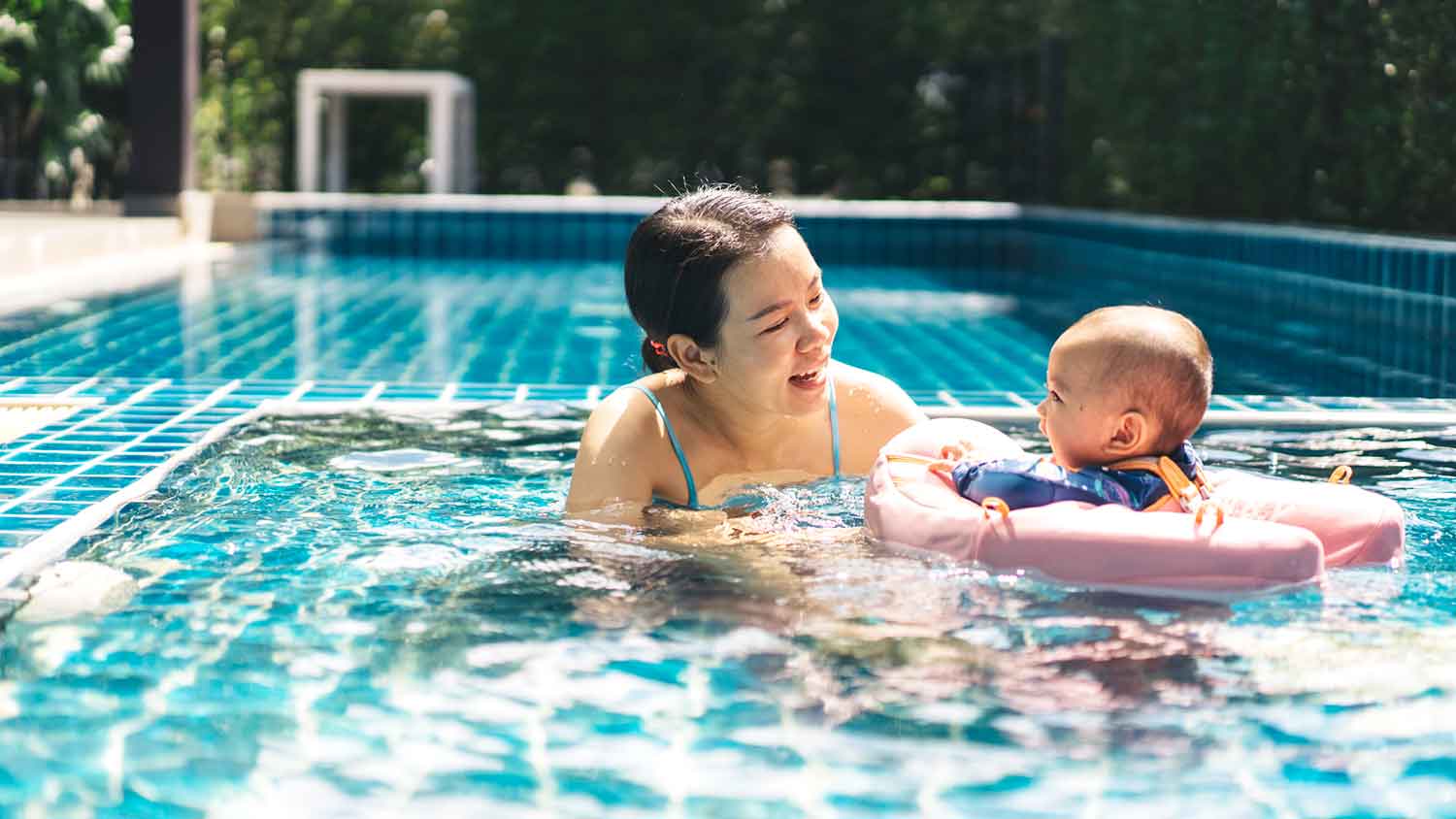 Mother and her infant child enjoying the swimming pool