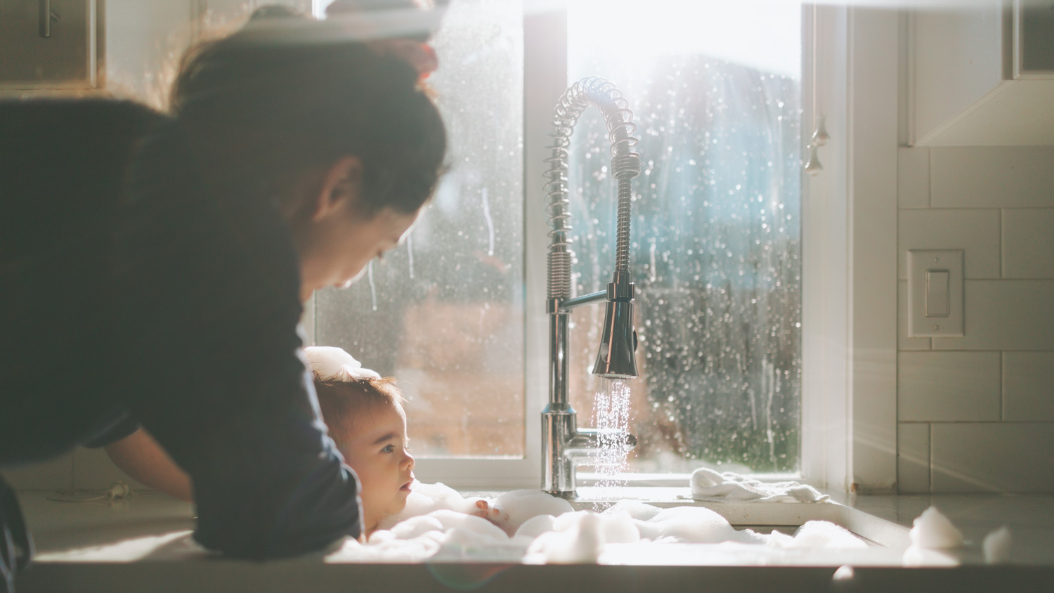 A mother bathing her son by the window