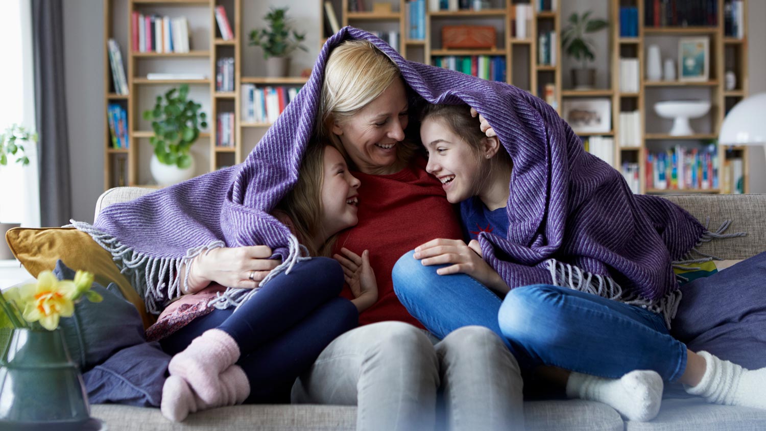 A mother and her daughters all wrapped under a blanket