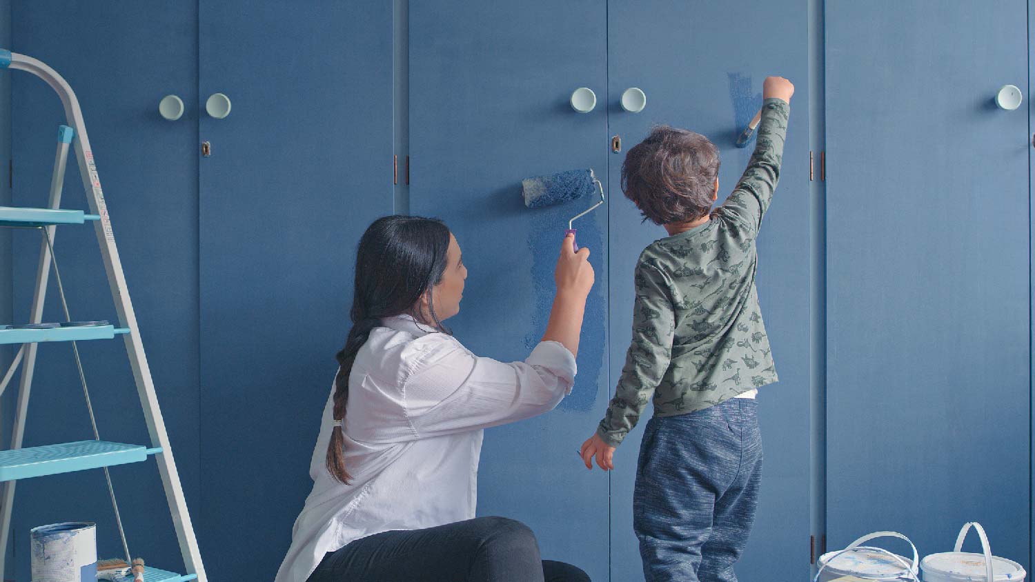 A mother and her son painting the wardrobe doors