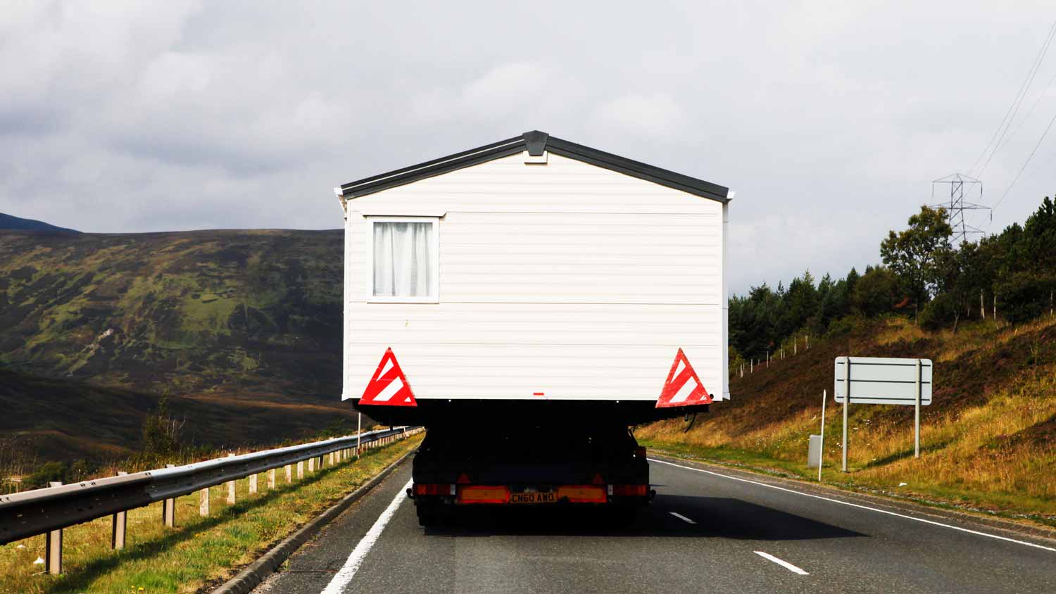 A moving truck transporting a shed on the road